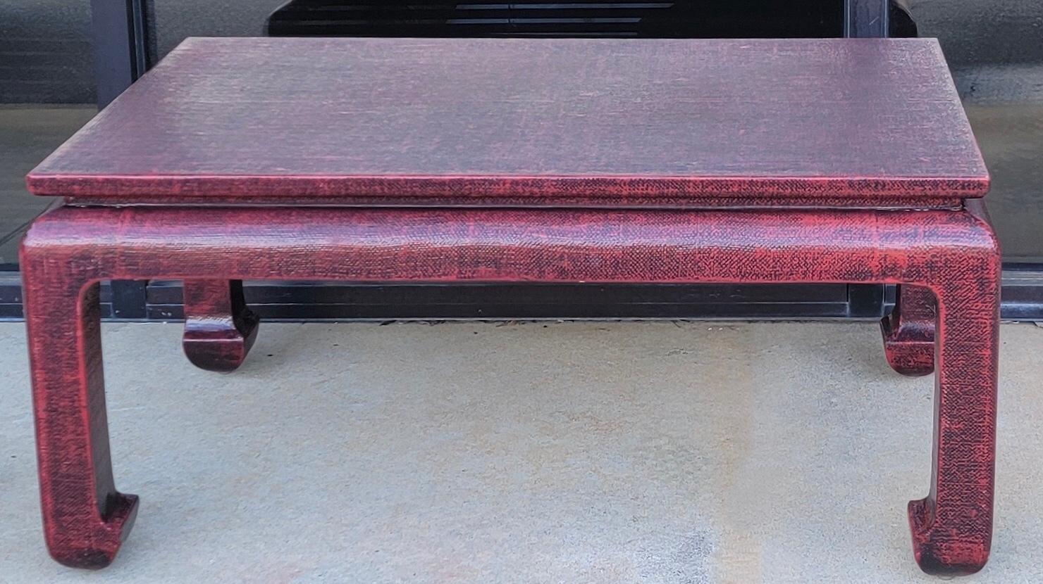 This is a red toned grasscloth wrapped ming style coffee table by Baker Furniture. It is marked andin very good condition.