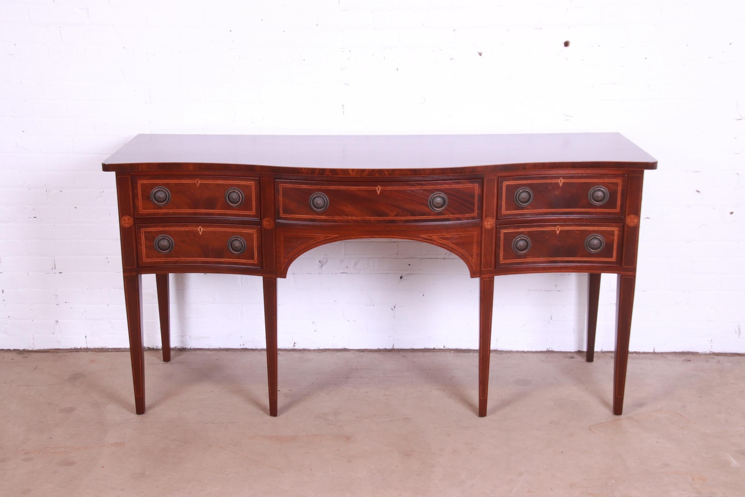 An exceptional Hepplewhite or Federal style serpentine front sideboard, buffet, or credenza

By Baker Furniture

USA, Mid-20th Century

Flame mahogany, with satinwood marquetry and banded inlay and original brass hardware.

Measures: 72