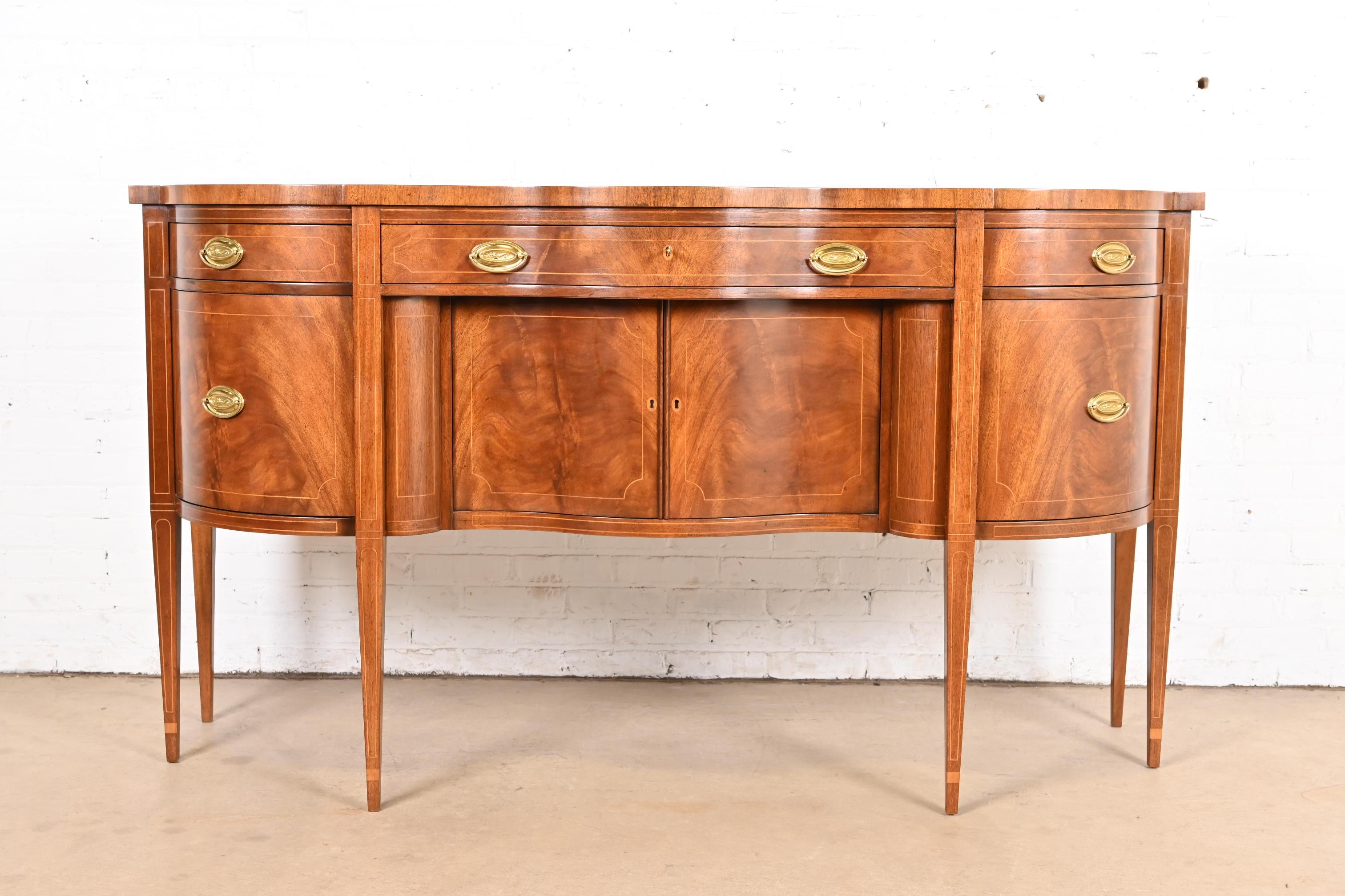 An exceptional Hepplewhite or Federal style sideboard, credenza, or buffet

By Baker Furniture

USA, Late 20th Century

Flame mahogany, with satinwood string inlay, and original brass hardware.

Measures: 72