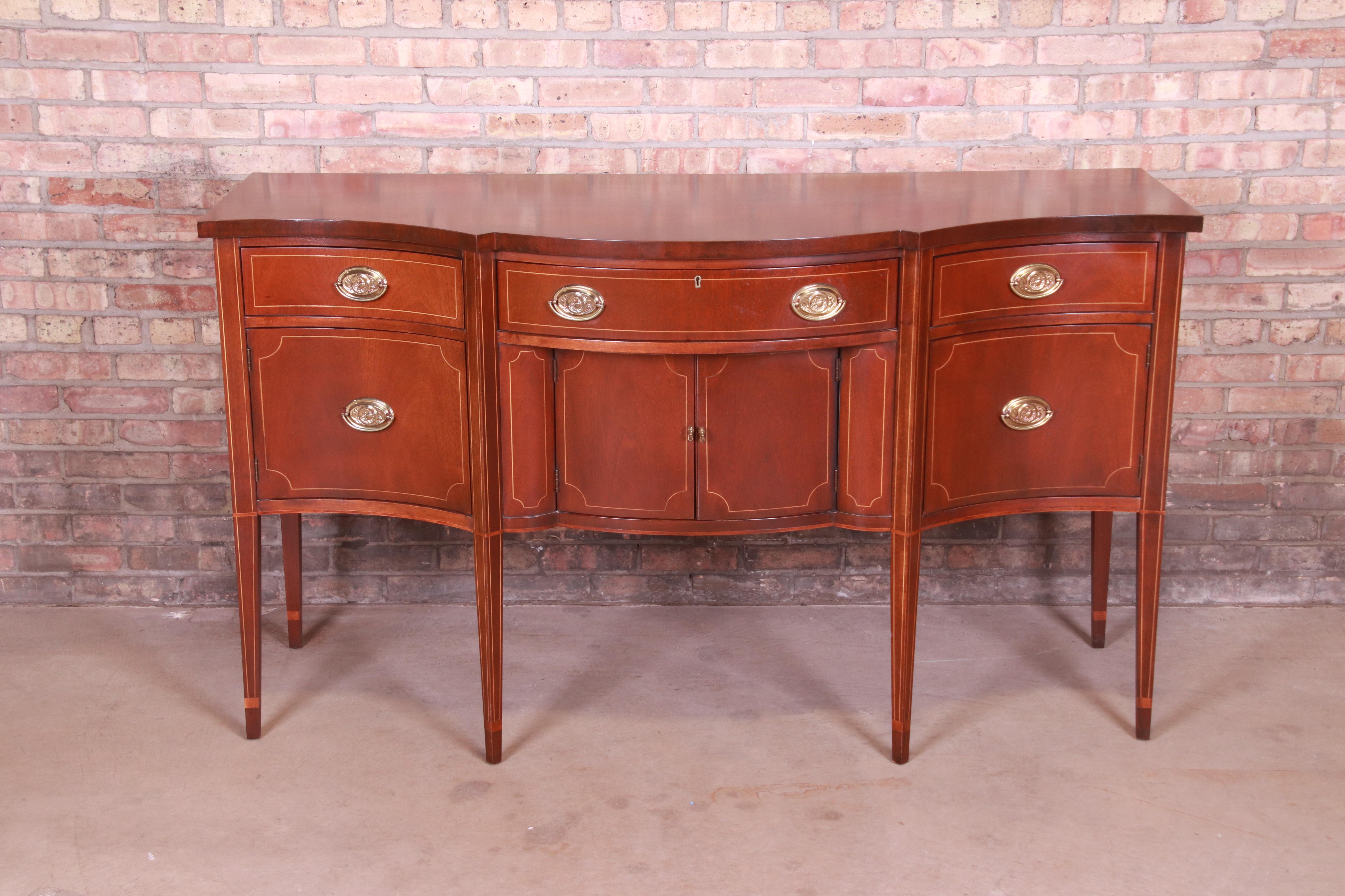 An exceptional Hepplewhite or Federal style sideboard, credenza, or buffet

By Baker Furniture

USA, late 20th century

Mahogany, with satinwood string inlay and original brass hardware.

Measures: 64.88