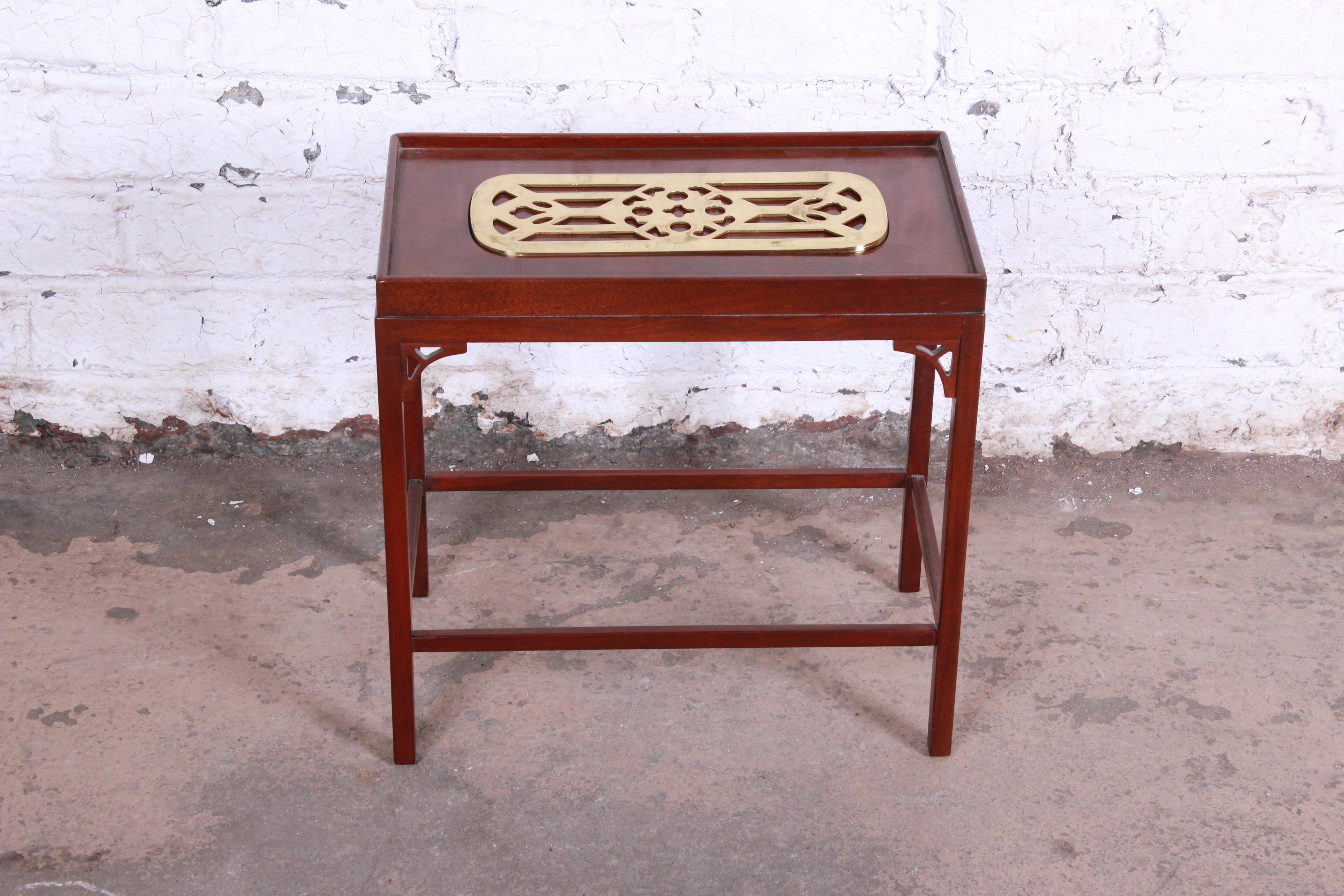 A beautiful mahogany and brass occasional table from the Historic Charleston Collection by Baker Furniture. The table features gorgeous mahogany wood grain and a unique brass insert on top. The original labels are present. The table is in excellent