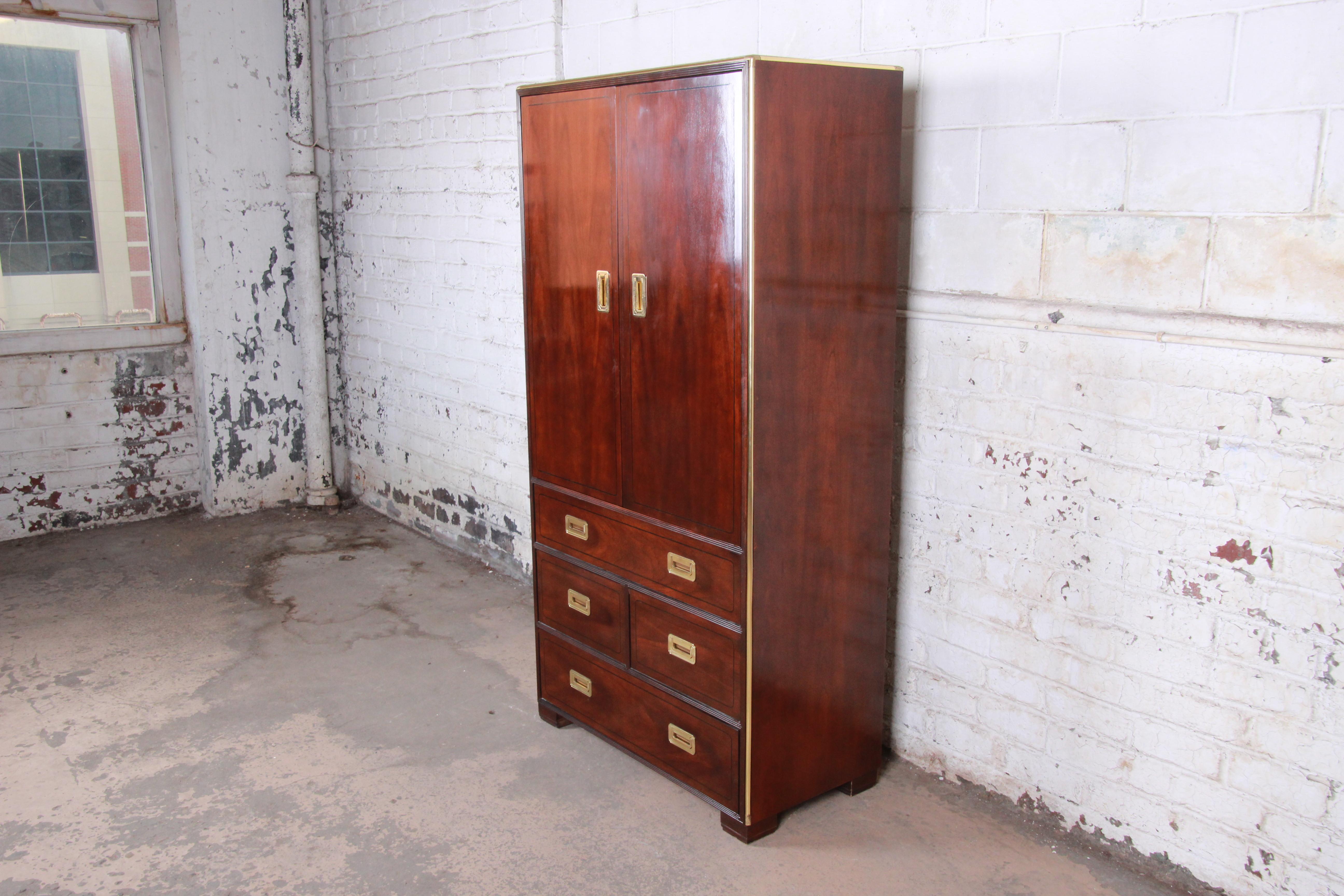 A gorgeous Hollywood Regency Campaign style armoire dresser or gentleman's chest

By Baker Furniture

USA, circa 1970s

Book-matched cherrywood and ebonized string inlay and brass trim and hardware

Measures: 38.25