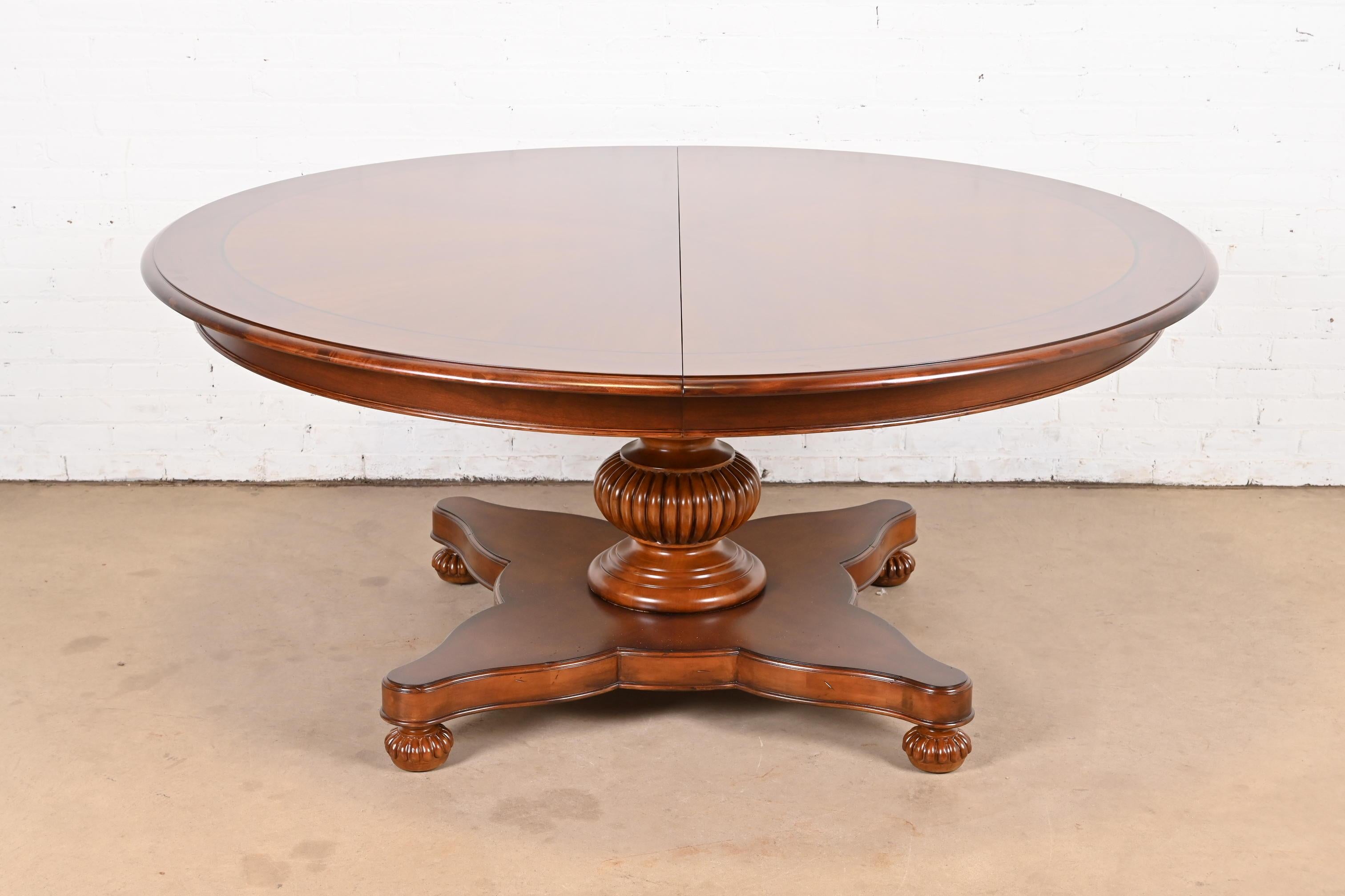 A gorgeous Italian Empire or Neoclassical style round pedestal extension dining table.

By Baker Furniture.

USA, Circa Late 20th Century

Gorgeous inlaid starburst design on top, with carved solid cherry wood pedestal.

Measures: 68