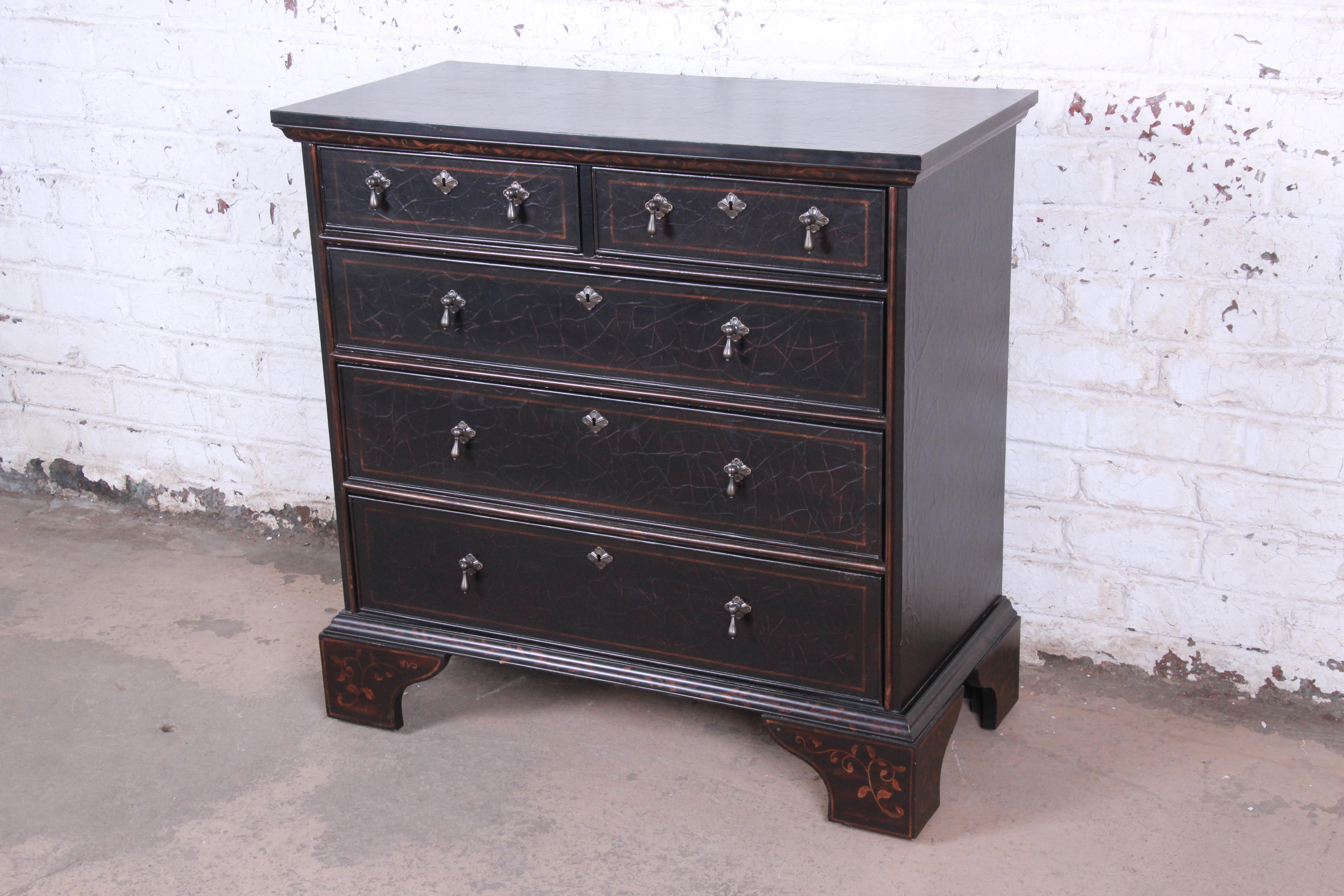 A gorgeous Italian style black lacquered dresser or chest of drawers by Baker Furniture. The chest features a unique antiqued black lacquered finish with painted floral details. It offers ample storage, with five dovetailed drawers. The original