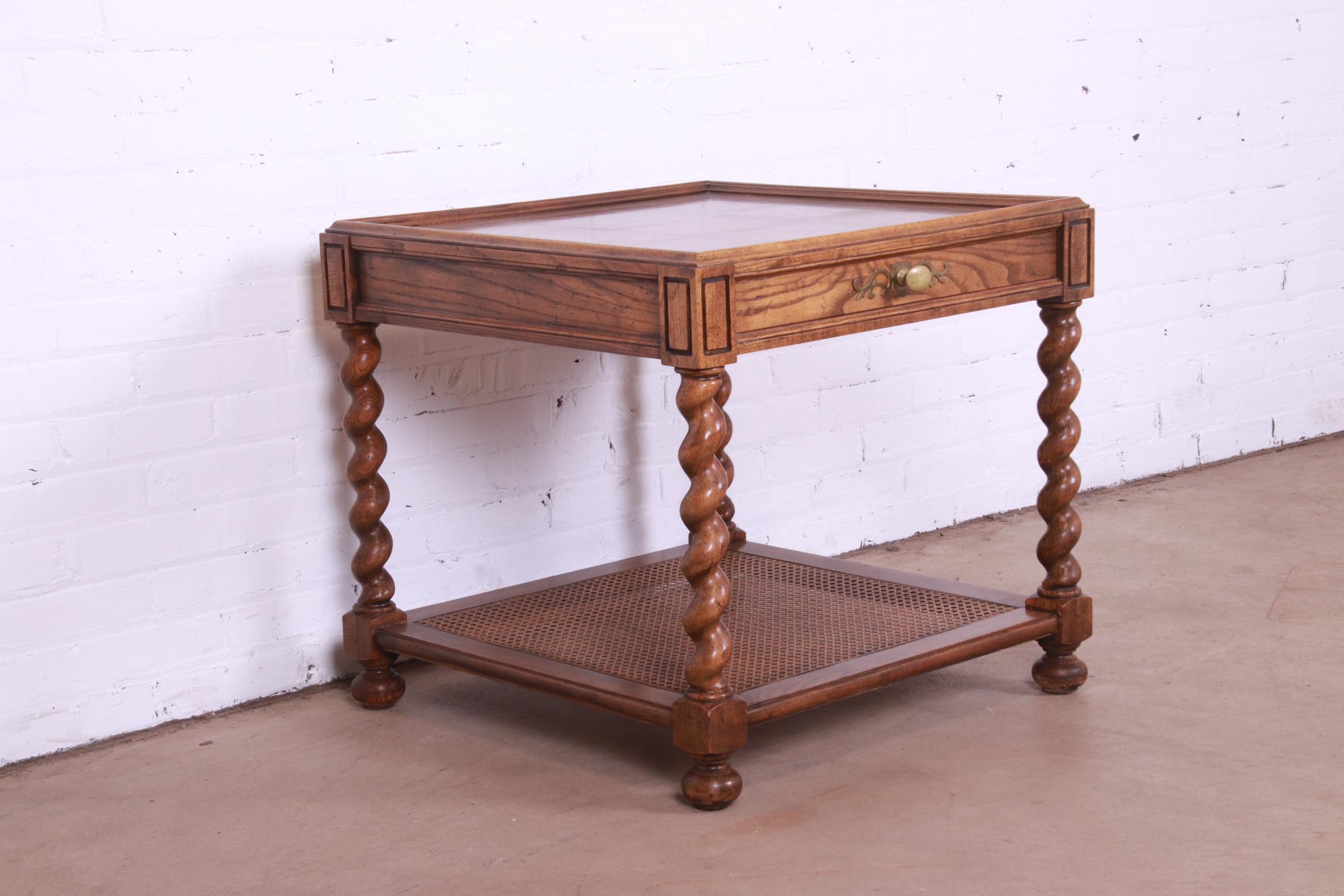 A gorgeous Jacobean style English barley twist tea table or occasional side table with parquet top

By Baker Furniture

USA, Circa 1960s

Carved oak, with burl wood parquetry, caned lower shelf, and original brass hardware.

Measures: 26