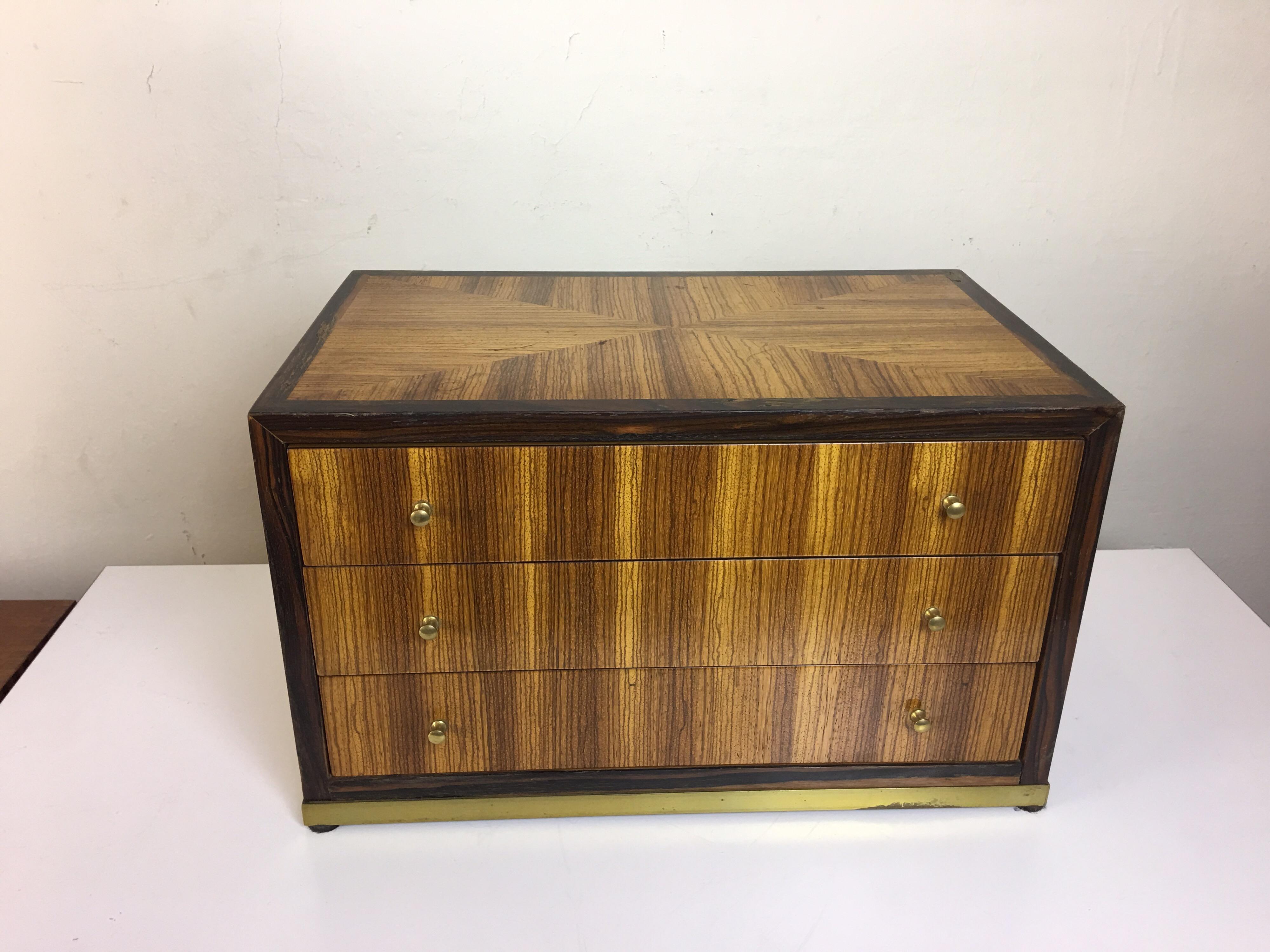 Rosewood and walnut Baker Furniture jewelry box/ chest. Three drawers for ample storage. Raised up on a brass square base with small brass knobs. Very elegant graceful design.