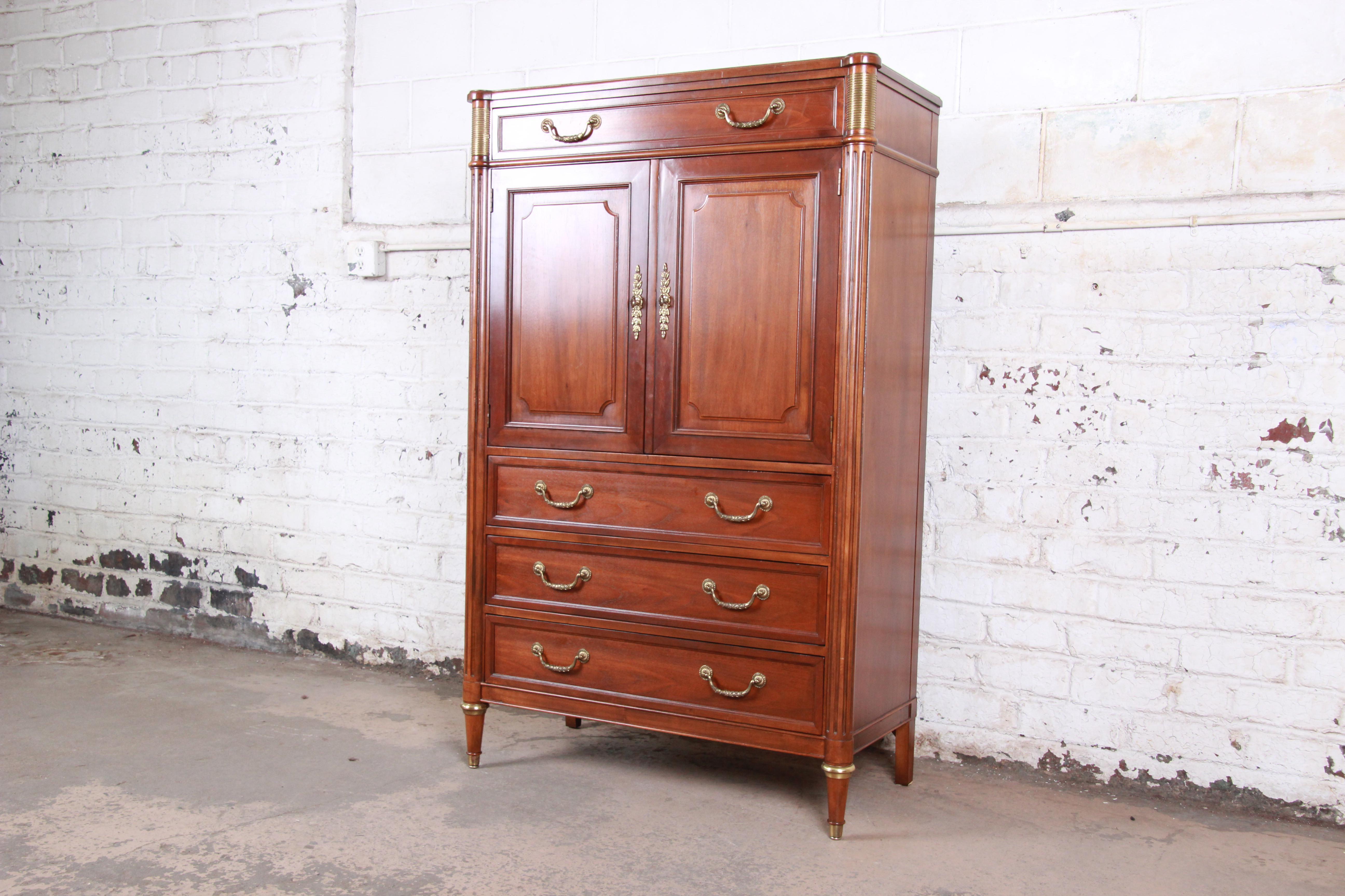 A gorgeous Louis XVI style French Regency gentleman's chest of drawers by Baker Furniture. The dresser features beautiful wood grain and nice brass details. It offers ample storage, with four dovetailed drawers as well as three cubbies and open