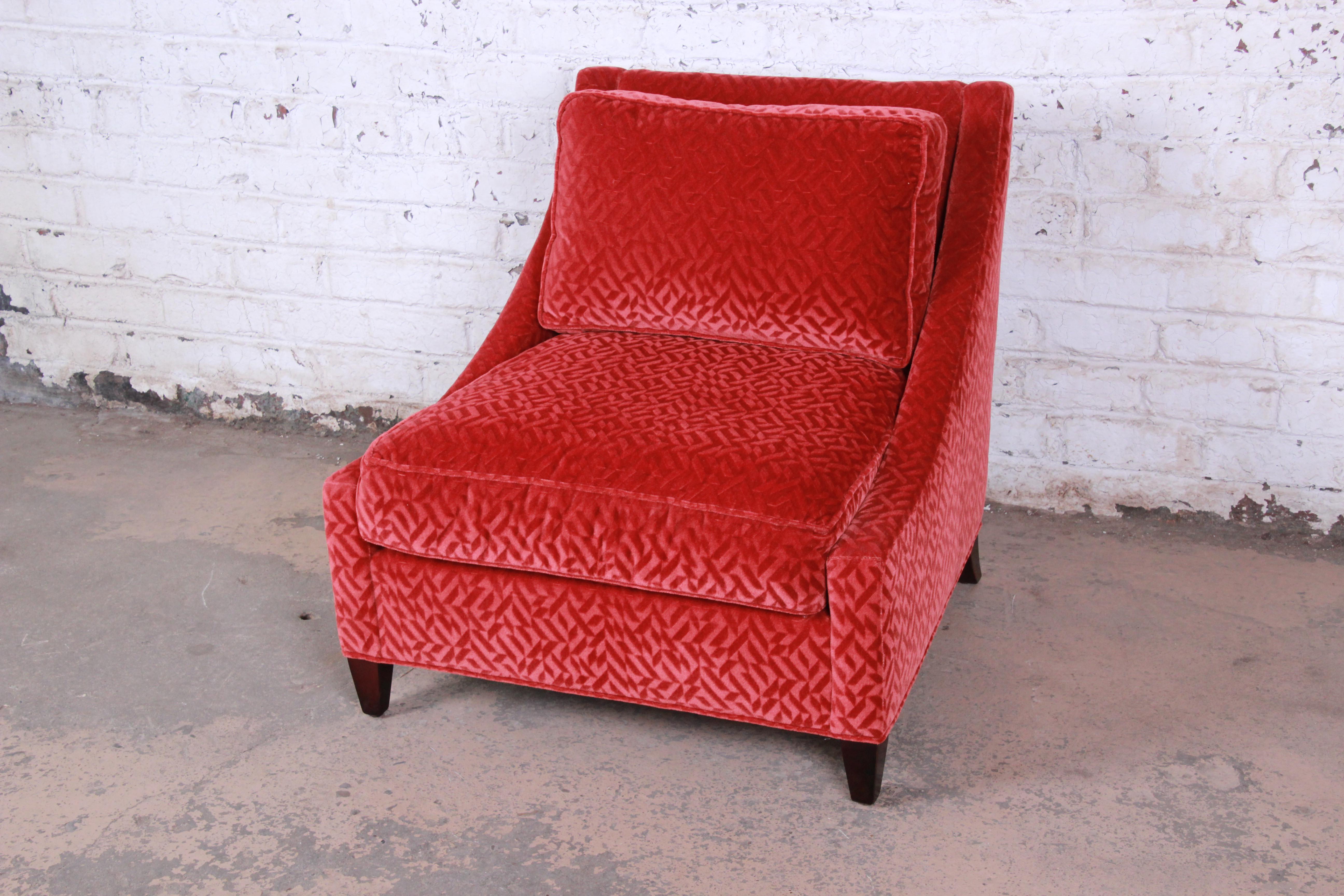 A gorgeous modern lounge chair by Baker Furniture. The chair features sleek modern lines with solid mahogany legs and beautiful red velvet upholstery. It is very plush and comfortable. The original Baker label is present. The chair is in excellent