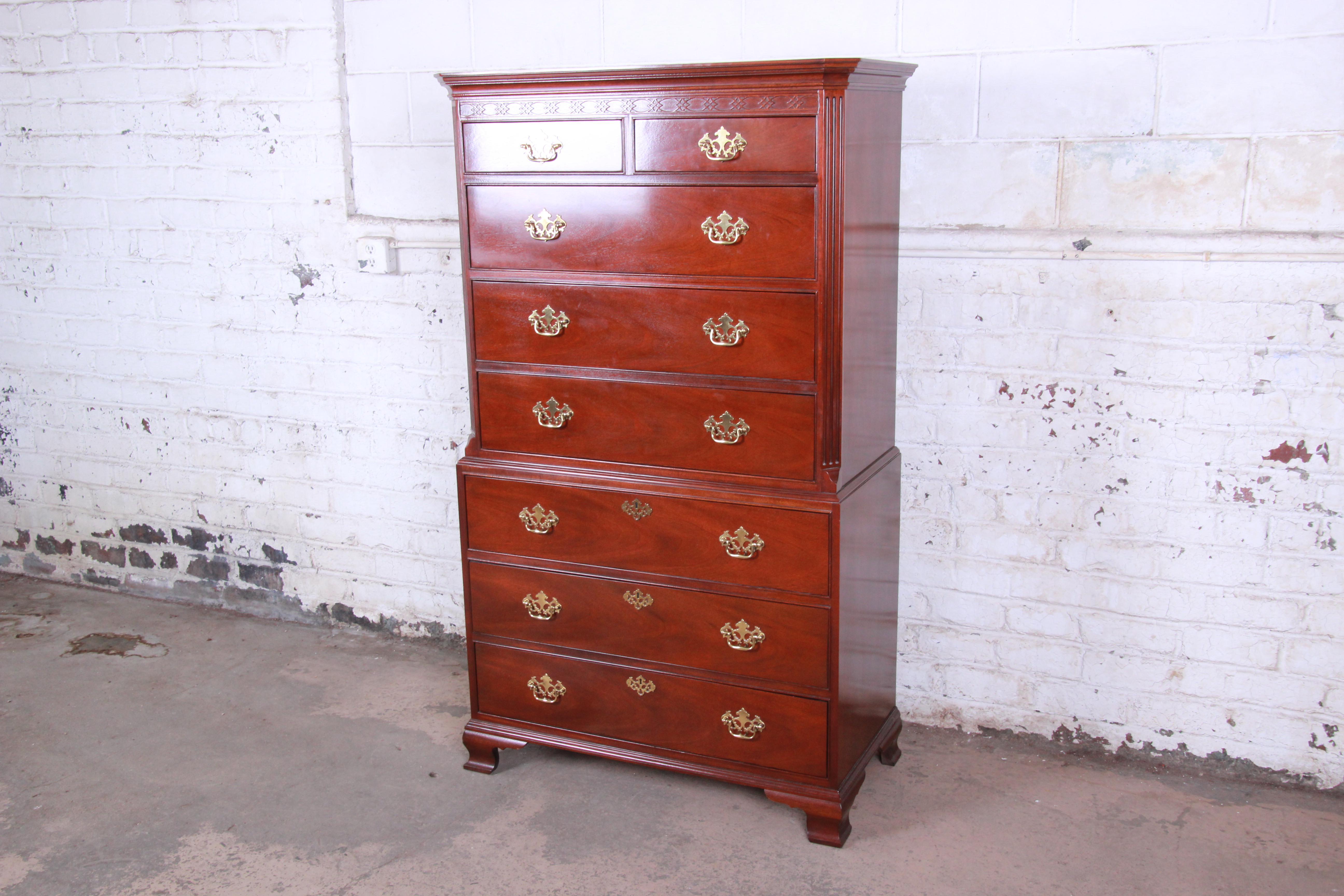 A gorgeous vintage Chippendale style mahogany highboy dresser by Baker Furniture. The dresser features stunning mahogany wood grain, with nice carved wood details and original brass hardware. It offers excellent storage, with eight deep dovetailed