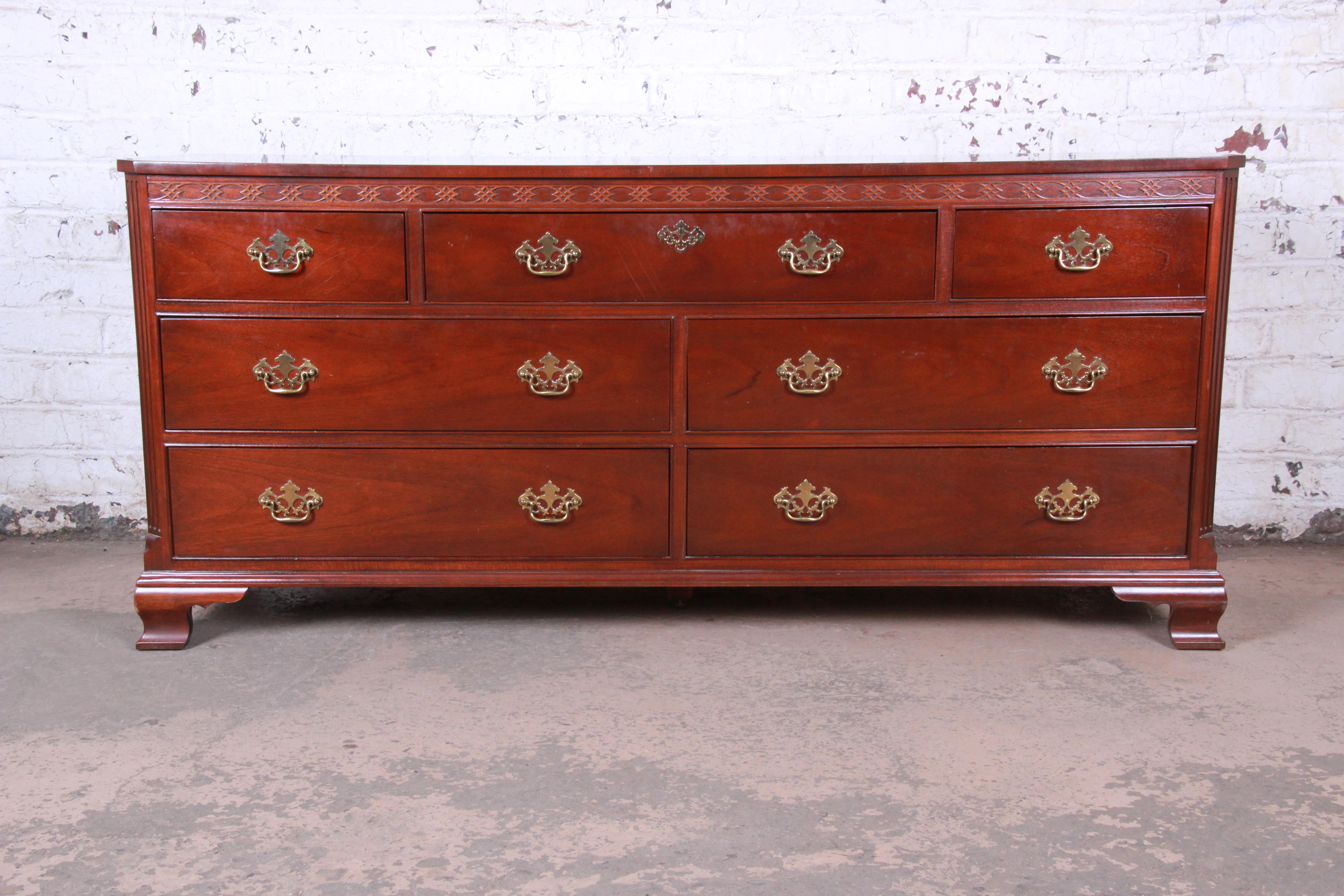 A gorgeous vintage Chippendale style mahogany long dresser by Baker Furniture. The dresser features stunning mahogany wood grain, with nice carved wood details and original brass hardware. It offers excellent storage, with seven deep dovetailed