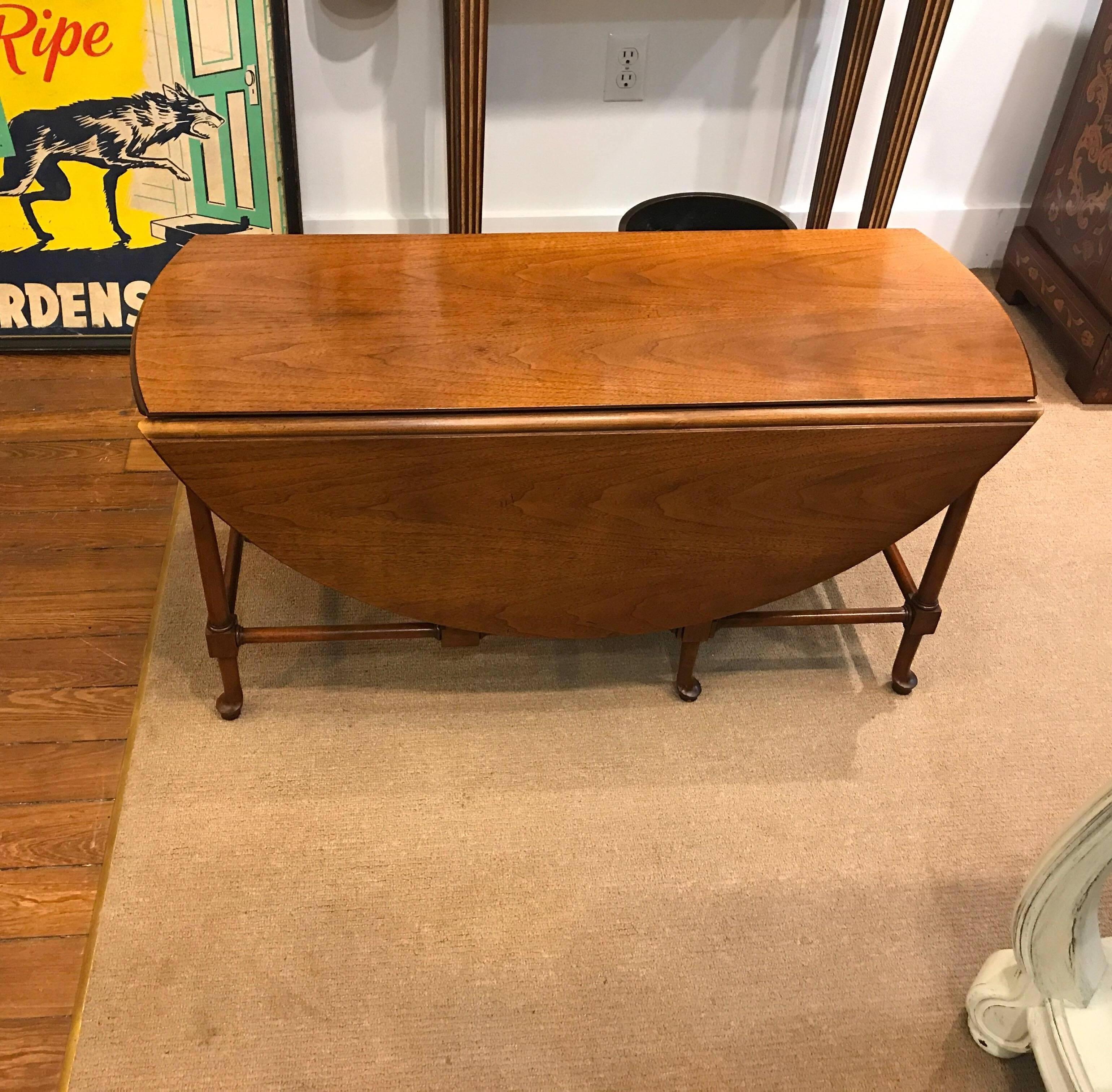 Traditionally styled mahogany drop-leaf coffee table made by Baker Furniture. A Great space saver that can be used with leaves down at 38 inches by 14.5 inches and when opened is 38 inches in diameter.