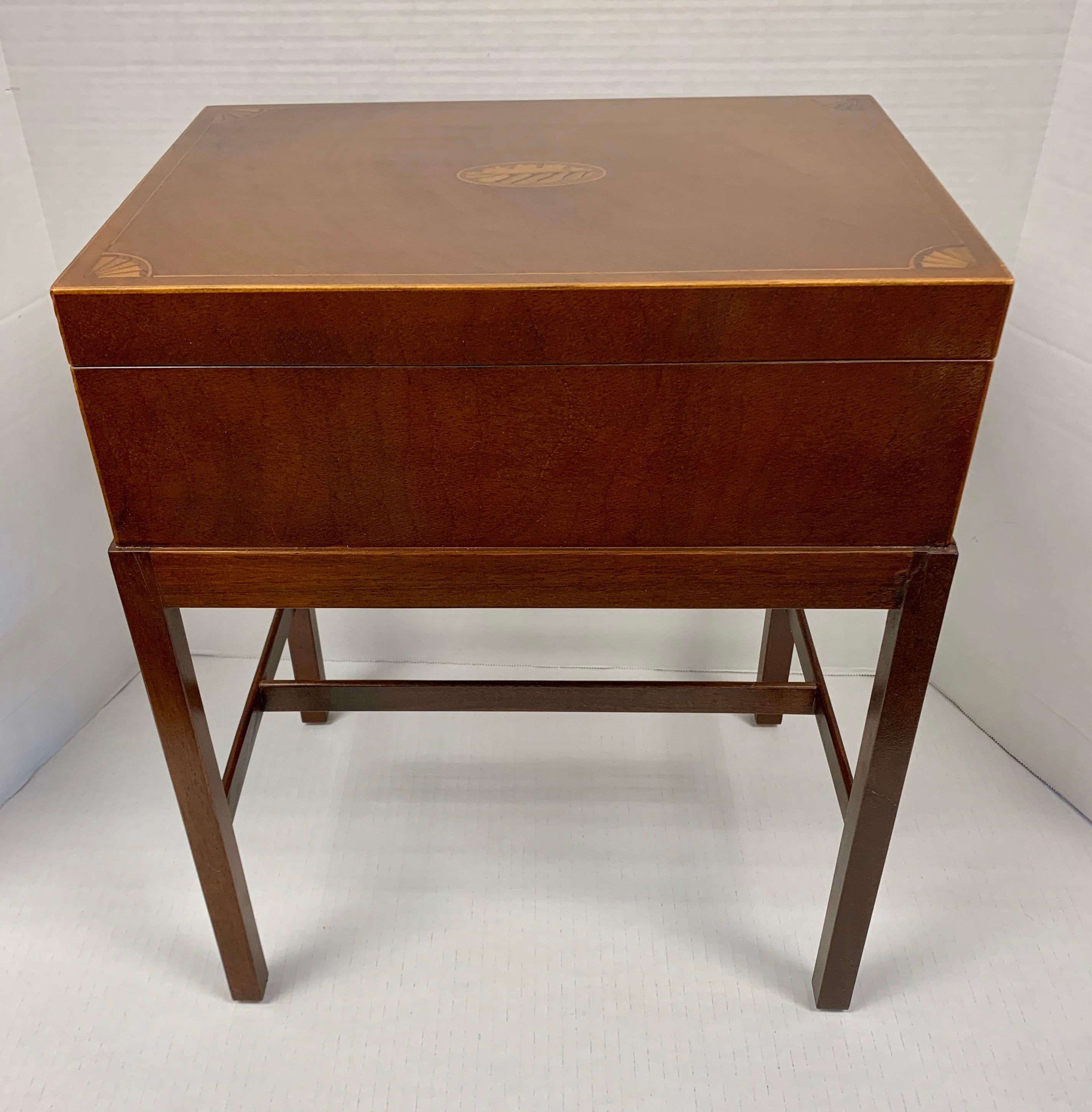 Handsome mahogany box on stand can function as a small side table while storing your smaller items like remote controls. Beautiful oval and line inlay detail. By Baker Furniture.