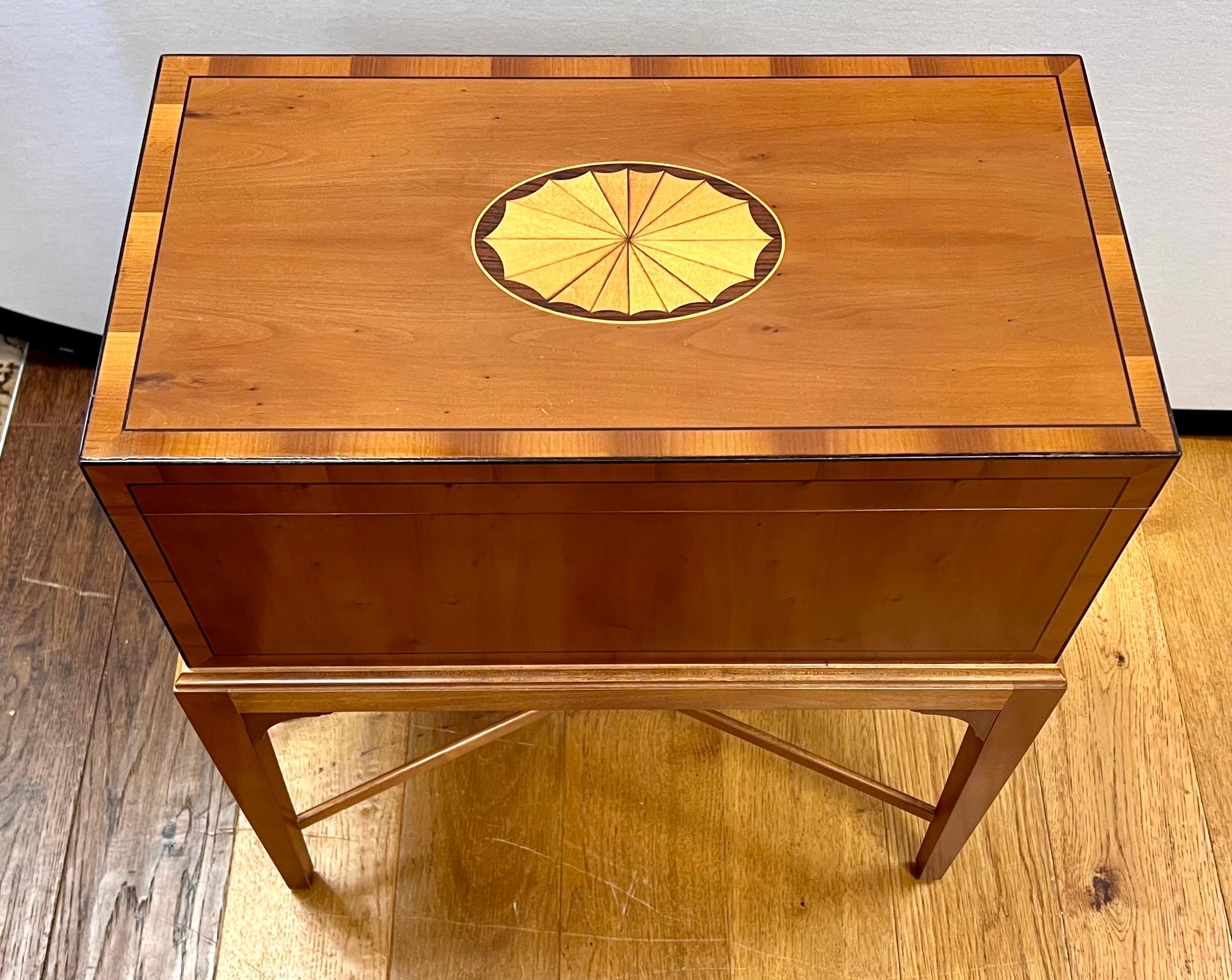 Small Baker Furniture flip top chest on x-base stand.  Features satinwood inlay on top and border.  Brass handles on side.