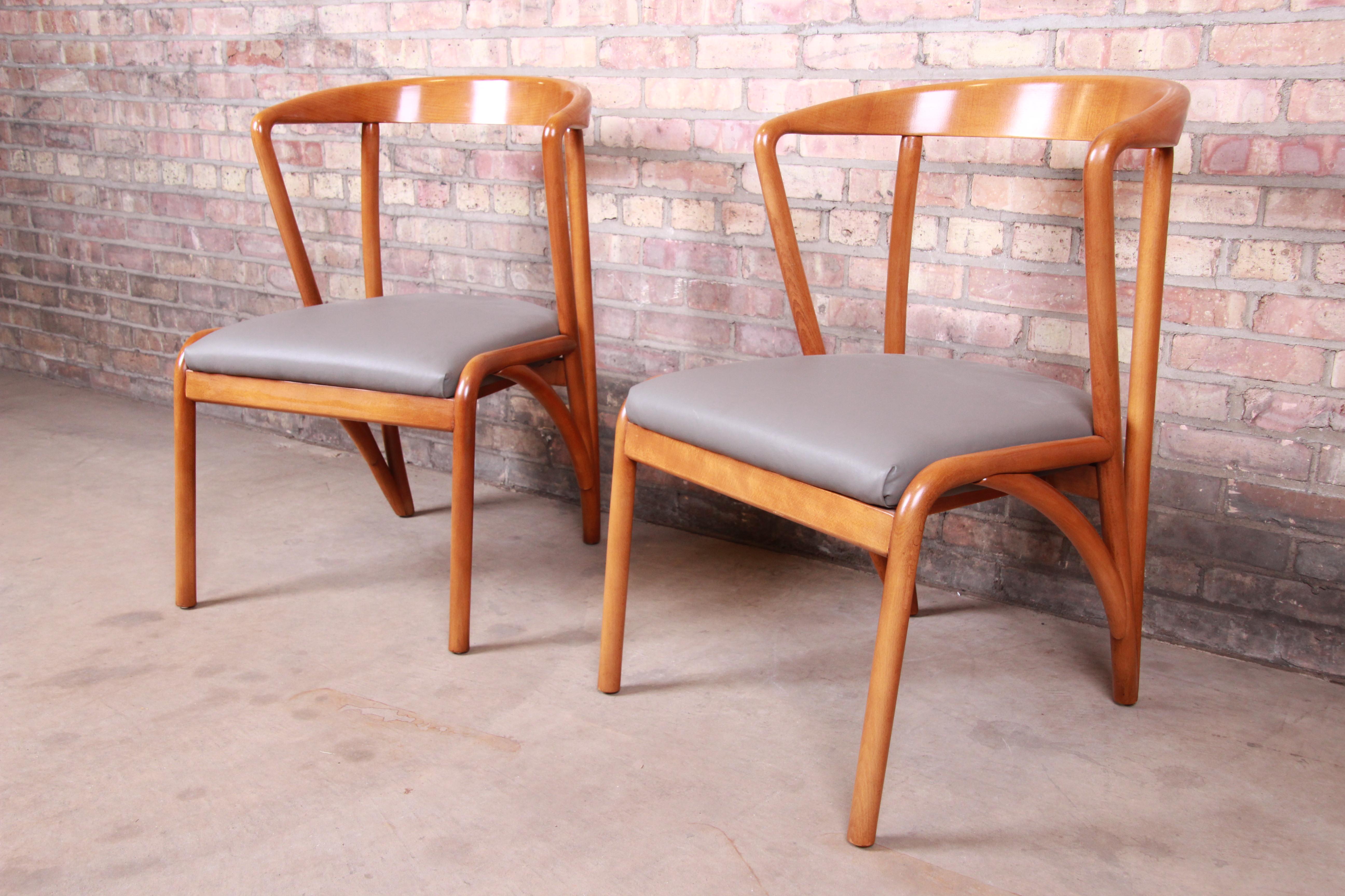 A gorgeous pair of Mid-Century Modern style armchairs

In the manner of Bertha Schaefer

By Baker Furniture

USA, early 21st century

Sculpted solid maple frames, with gray vinyl upholstery.

Measures: 22