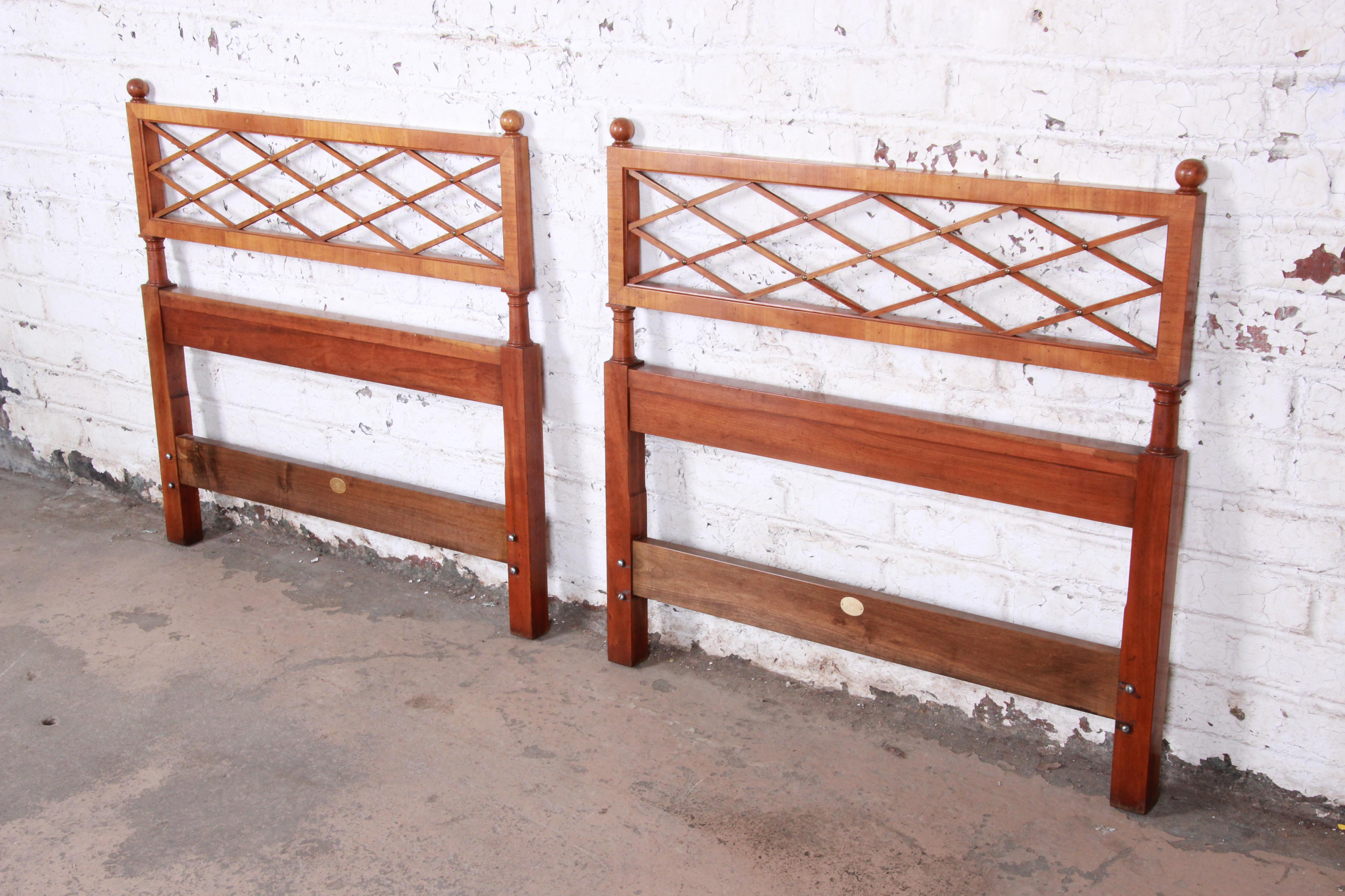 A gorgeous pair of midcentury twin headboards by Baker Furniture. The headboards feature beautiful wood grain and a nice lattice design with brass details. This pair was sold by high-end Chicago retailer John A Colby & Sons. The original Baker label