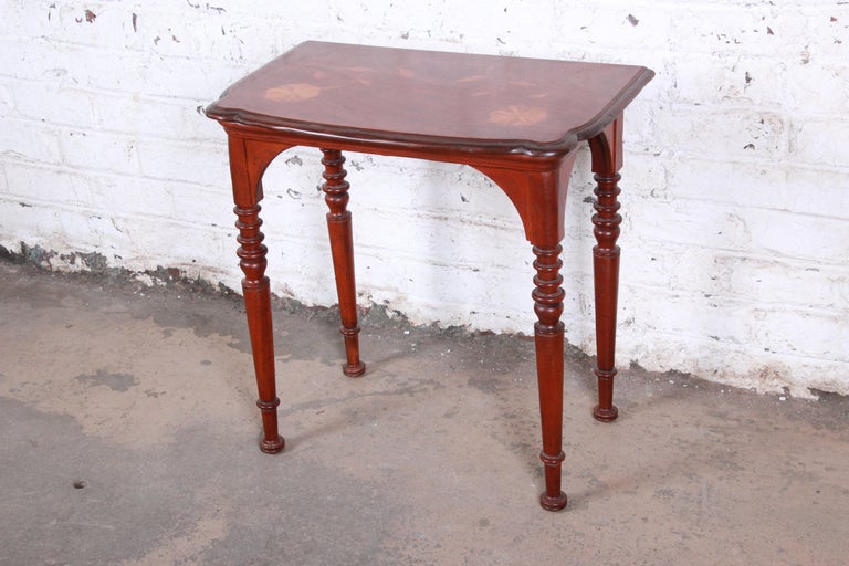 An exceptional early American Colonial style console table from the Milling Road collection by Baker Furniture. The table features gorgeous wood grain with unique inlaid floral details and turned legs. The original label is present. The table is in
