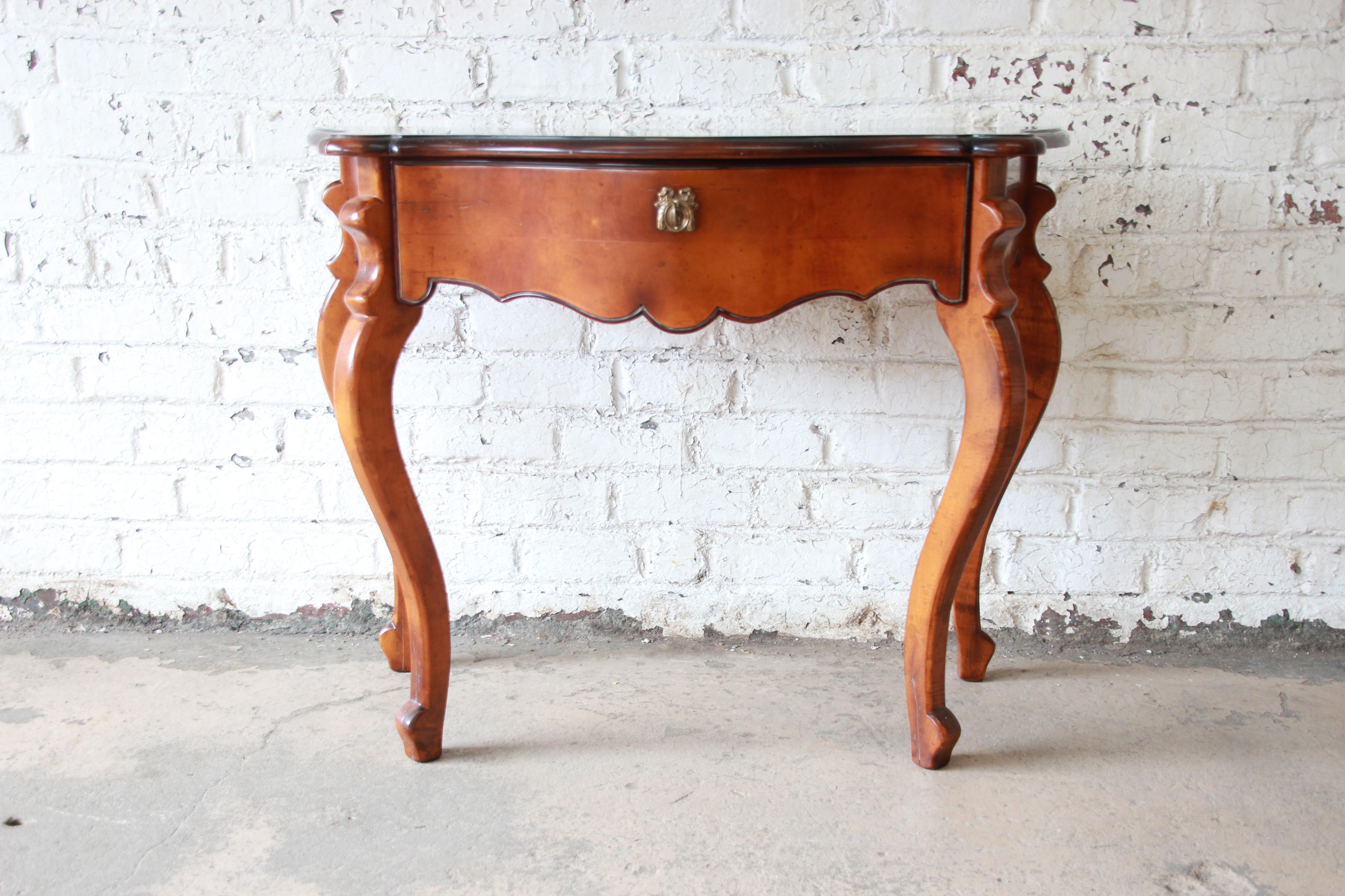 Offering a beautiful Baker Furniture maple French console table. Each table has a beautiful maple finish with darker contrasting tops. These pieces offer classical French lines and details and come with a locking key. They both are in great vintage