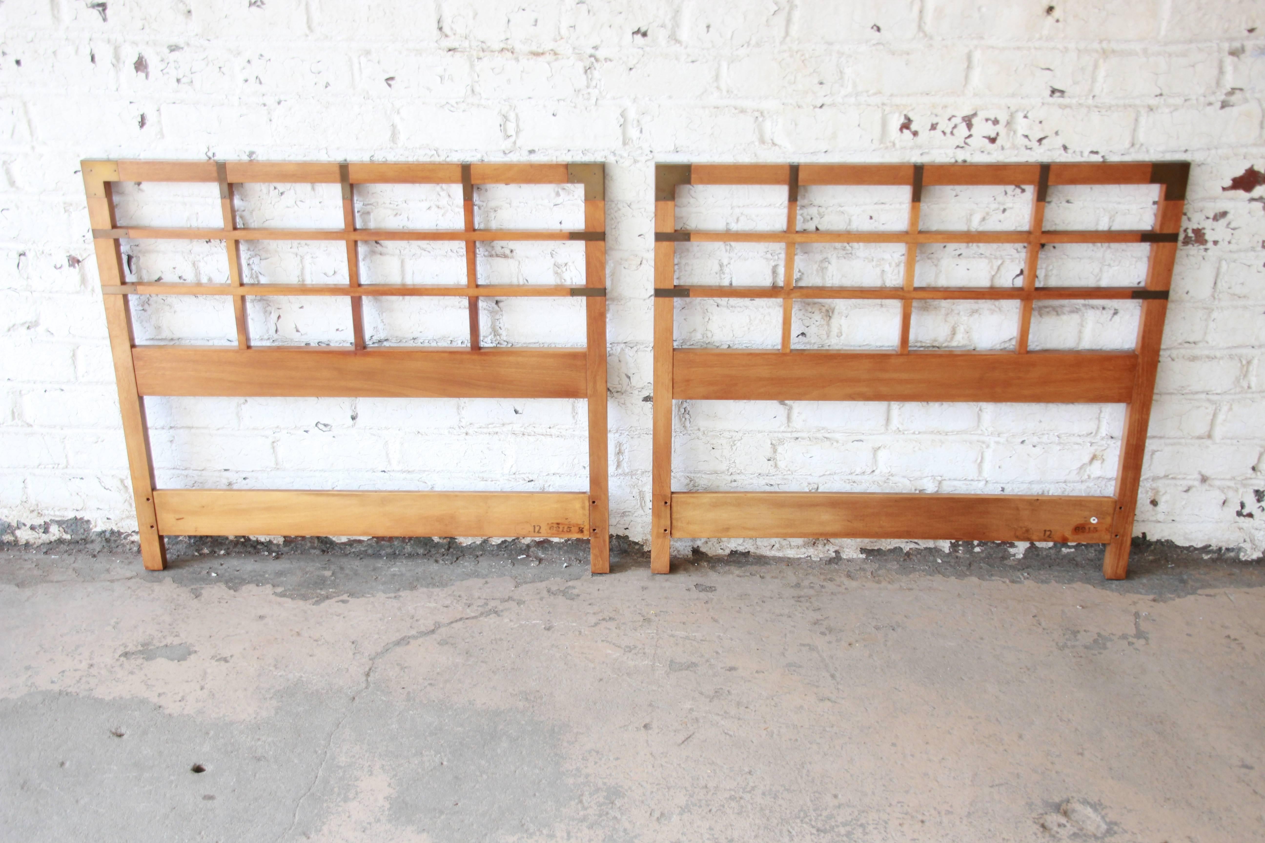 A beautiful pair of midcentury twin size Campaign style headboards from the Milling Road line by Baker Furniture. The headboards have nice brass details and clean midcentury lines. They can be placed together to form a king-size headboard. They are