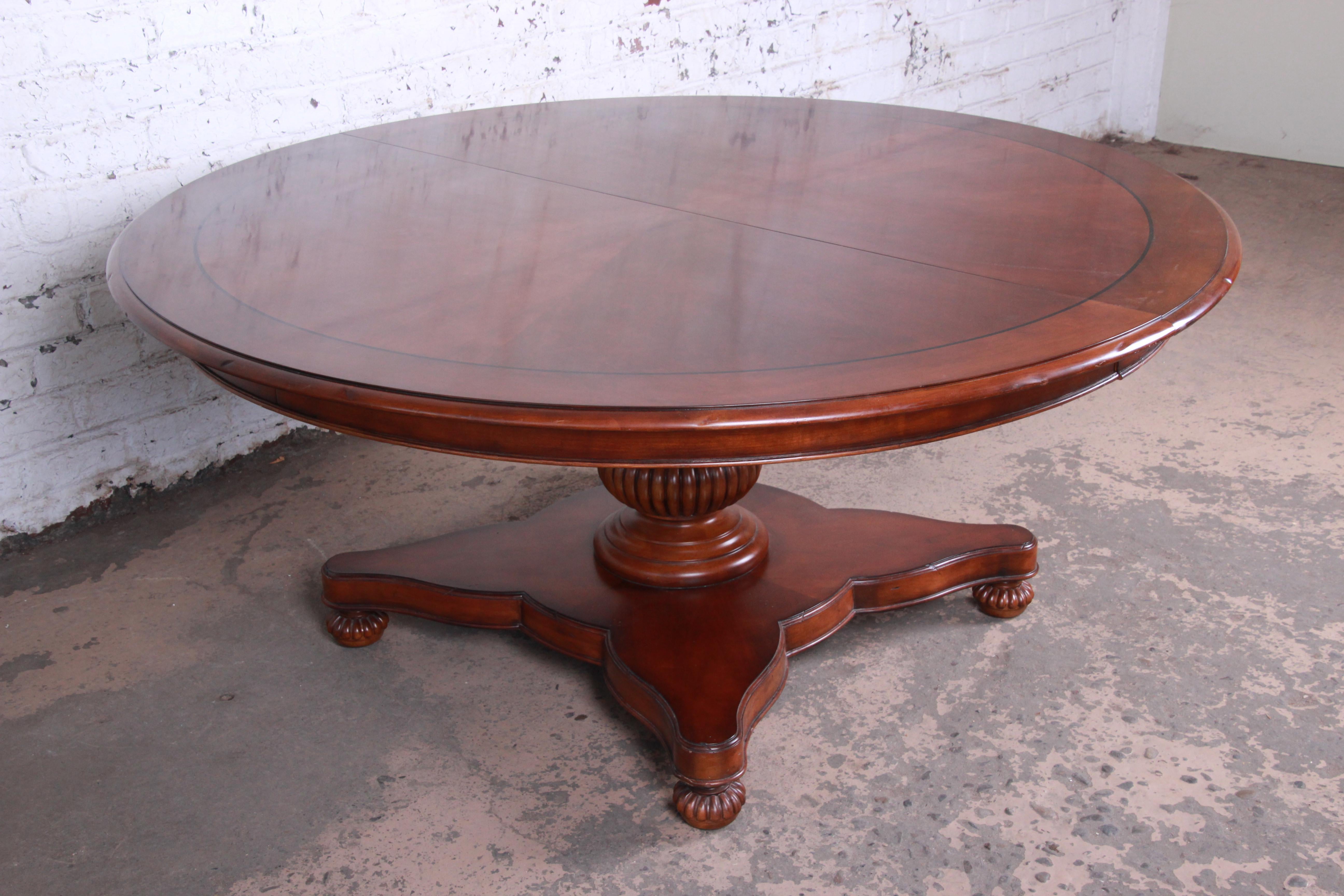 An exceptional neoclassical style banded mahogany dining or center table from the Milling Road Collection by Baker Furniture. The table features gorgeous mahogany wood grain and a nice traditional neoclassical style. It has a beautiful carved