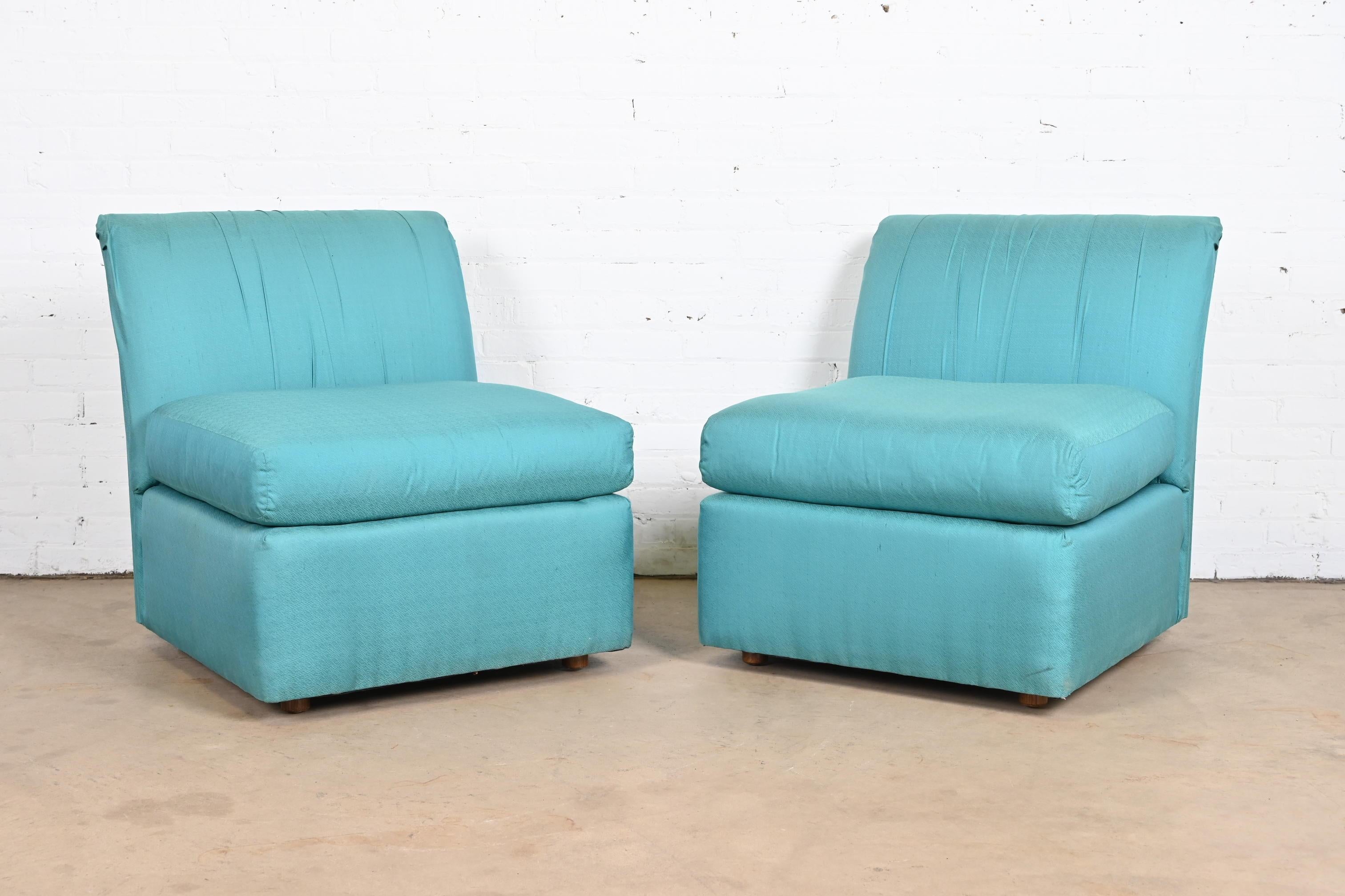 A stunning pair of Modern armless silk slipper chairs or lounge chairs with original turquoise silk upholstery.

By Baker Furniture.

USA, circa 1970s.

Measures: 28