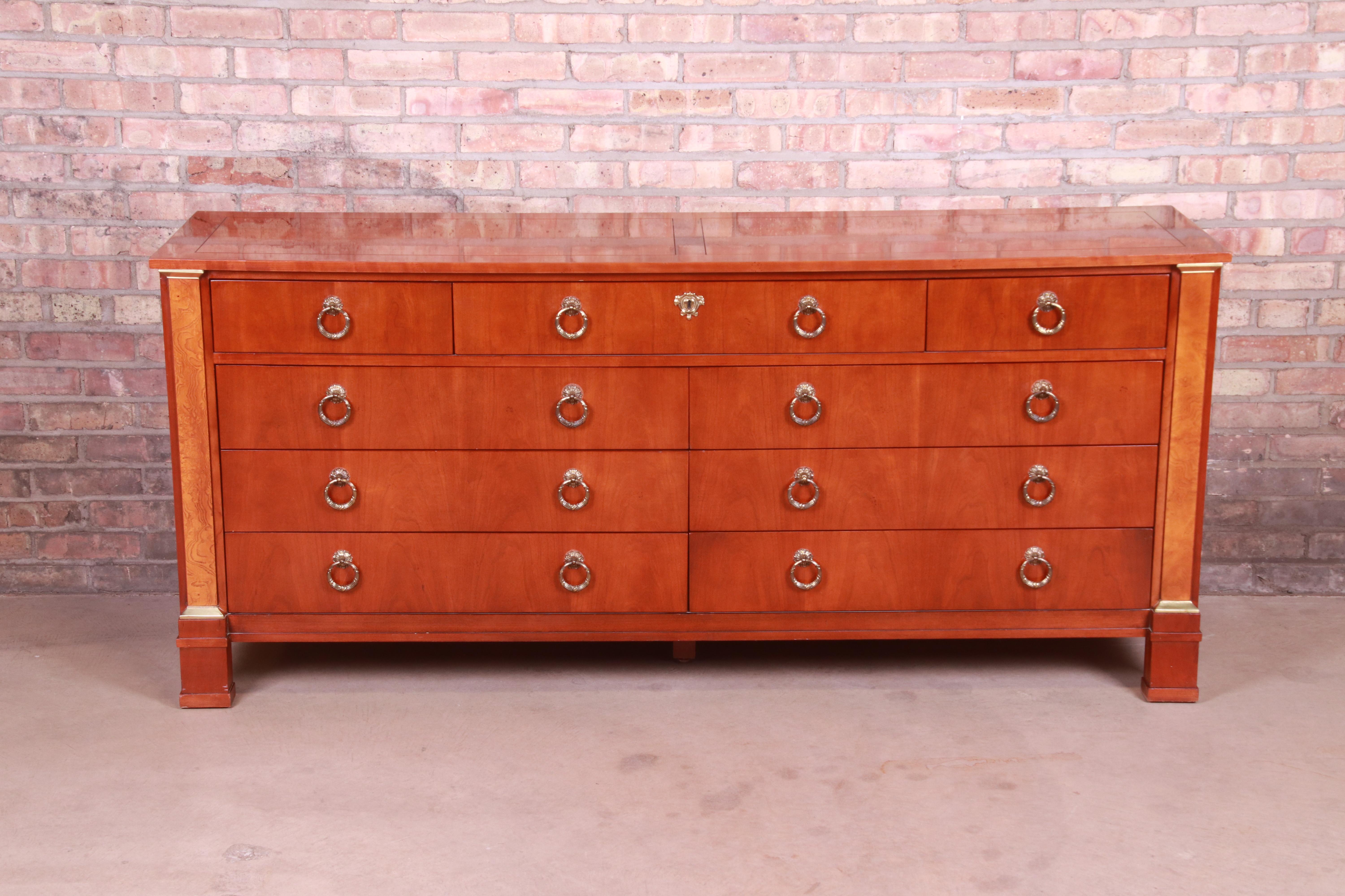 A gorgeous neoclassical or Empire style nine-drawer dresser or credenza

By Baker Furniture

USA, late 20th century

Cherrywood, with burl wood columns and original brass hardware and accents.

Measures: 72