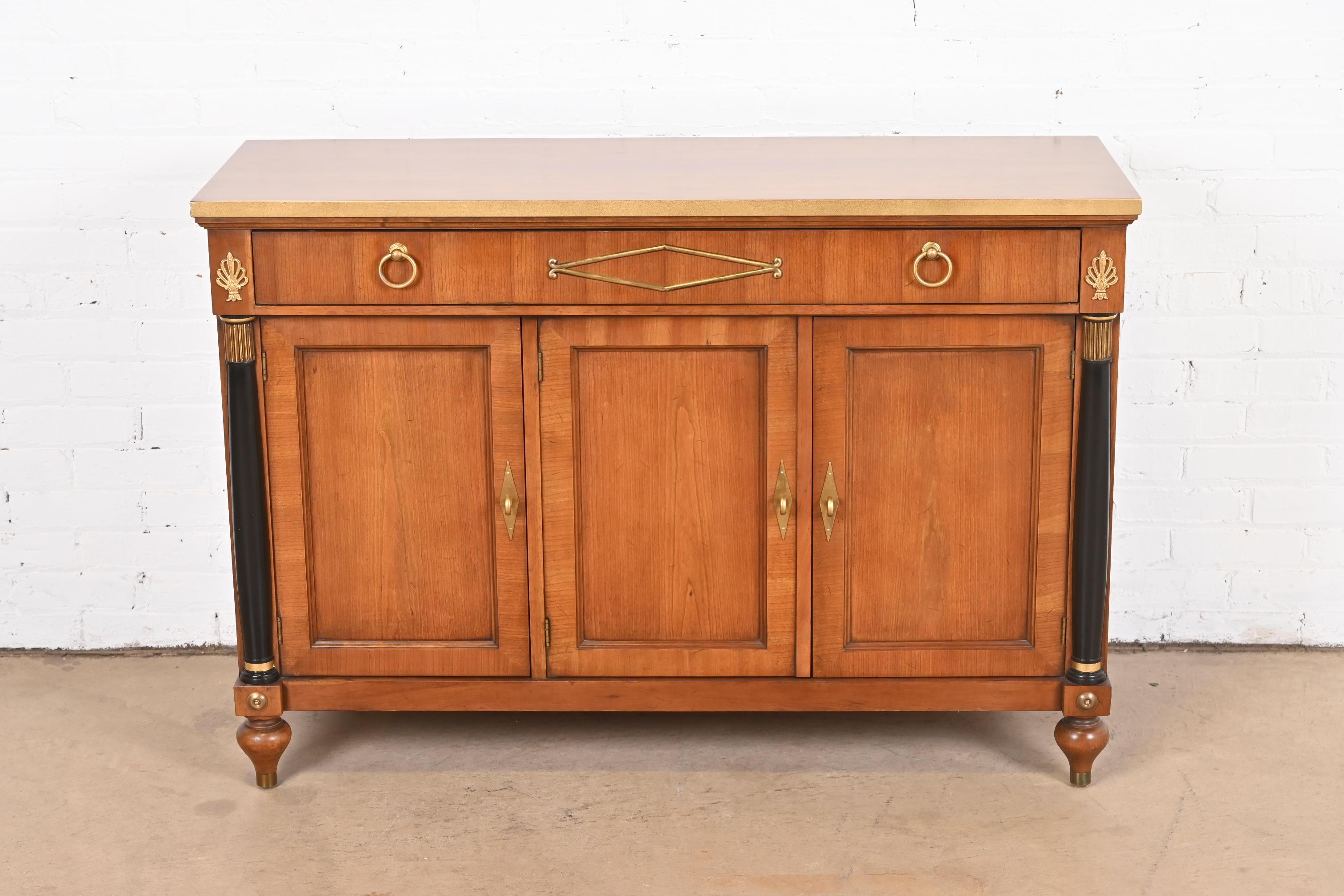 A gorgeous Neoclassical or Empire style sideboard, credenza, or bar cabinet

By Baker Furniture

USA, Circa 1960s

Beautiful cherry wood, with ebonized columns, gold gilt trim, and original brass hardware.

Measures: 48