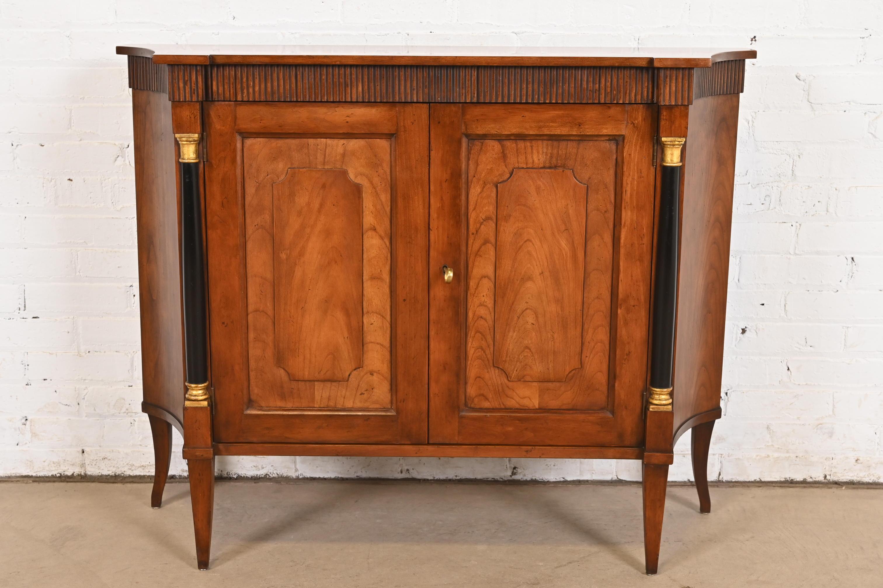 A gorgeous Neoclassical, Regency, or Empire style sideboard, console, credenza, or bar cabinet

By Baker Furniture

USA, Circa 1960s

Beautiful carved cherry wood, with ebonized and gold gilt columns. Shelves are adjustable. Cabinet locks, and key