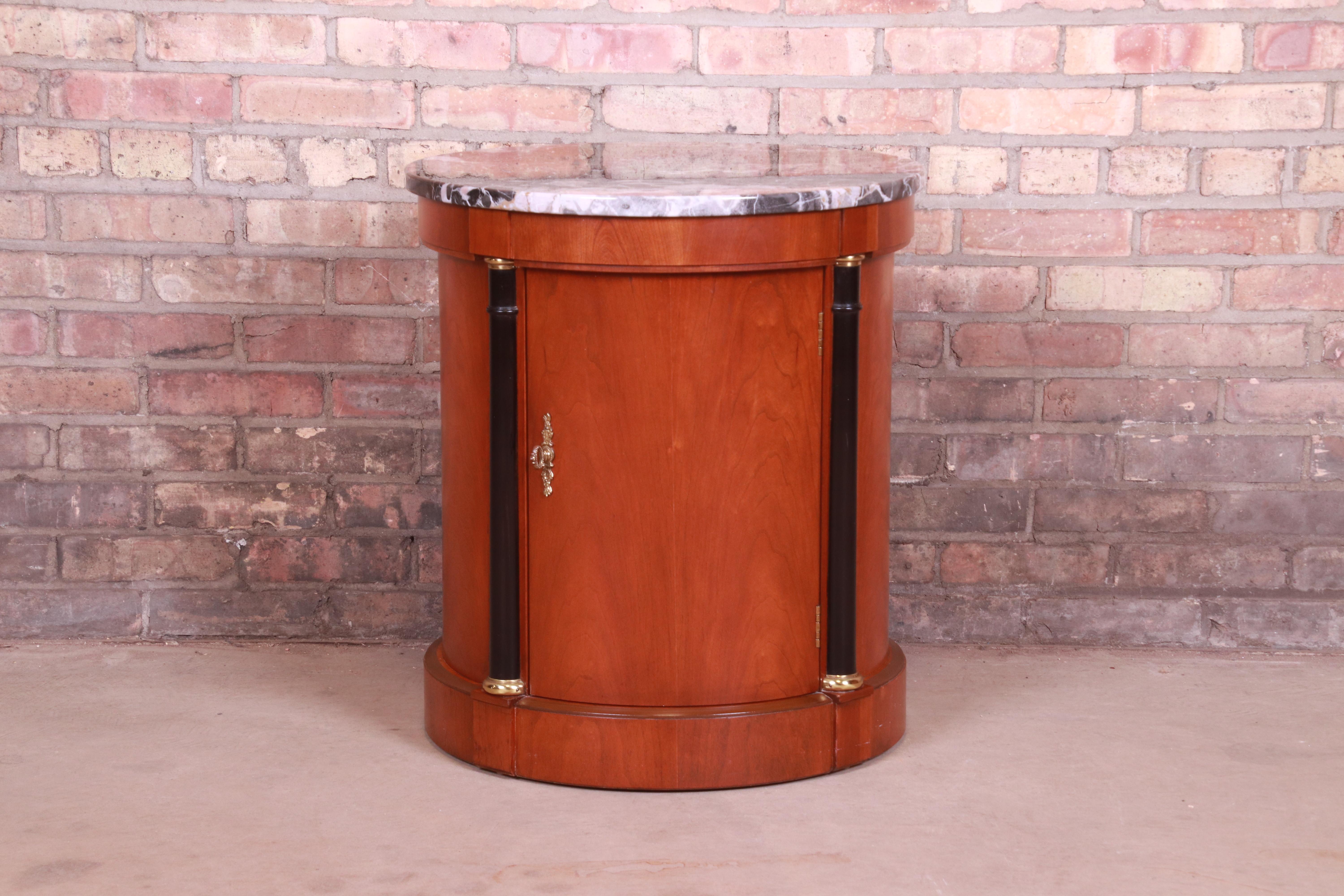 A gorgeous Neoclassical or Empire style nightstand or side table

By Baker Furniture

USA, late 20th century

Cherrywood, with ebonized columns, marble top, and original brass hardware and accents.

Measures: 22