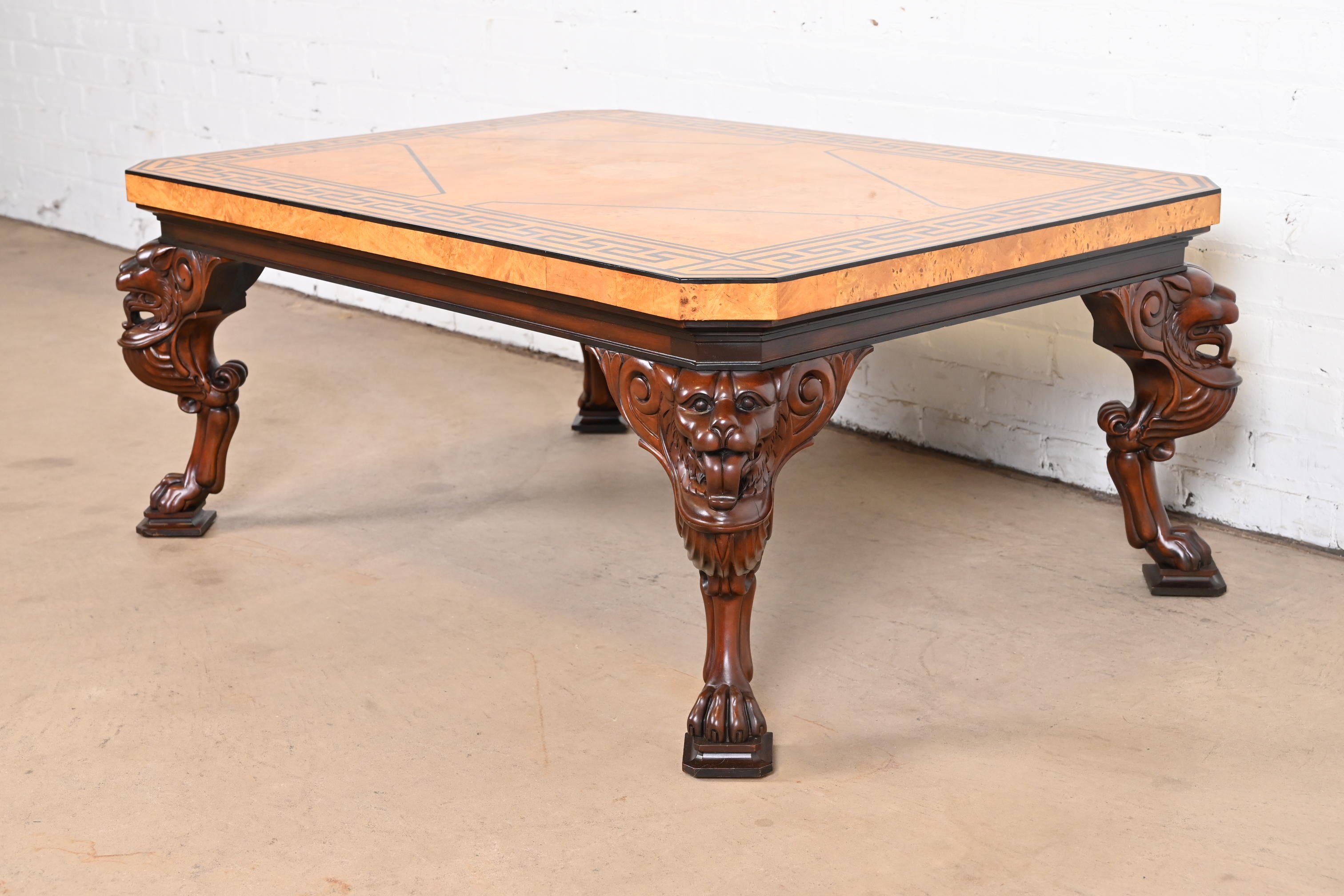 An outstanding neoclassical or Regency style coffee or cocktail table

By Baker Furniture

USA, late 20th century

Burled olive wood top, with ebonized Greek Key design, on carved solid mahogany lion form legs terminating in paw