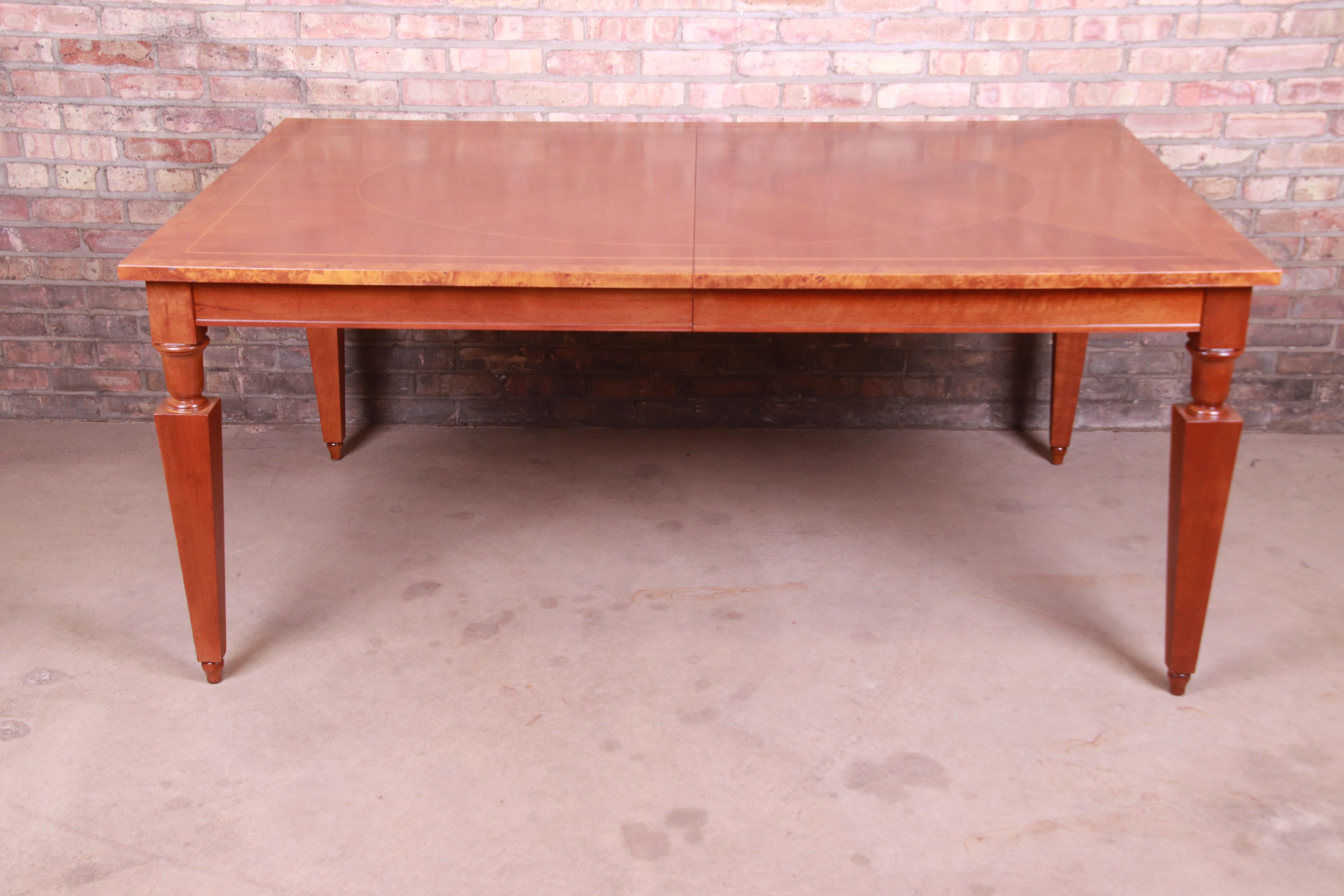 Une belle table à manger à rallonge de style néoclassique

Par Baker Furniture,

États-Unis, vers les années 1990

Bois de cerisier marqueté et assorti aux livres, avec bande de ronce.

Mesures : 70