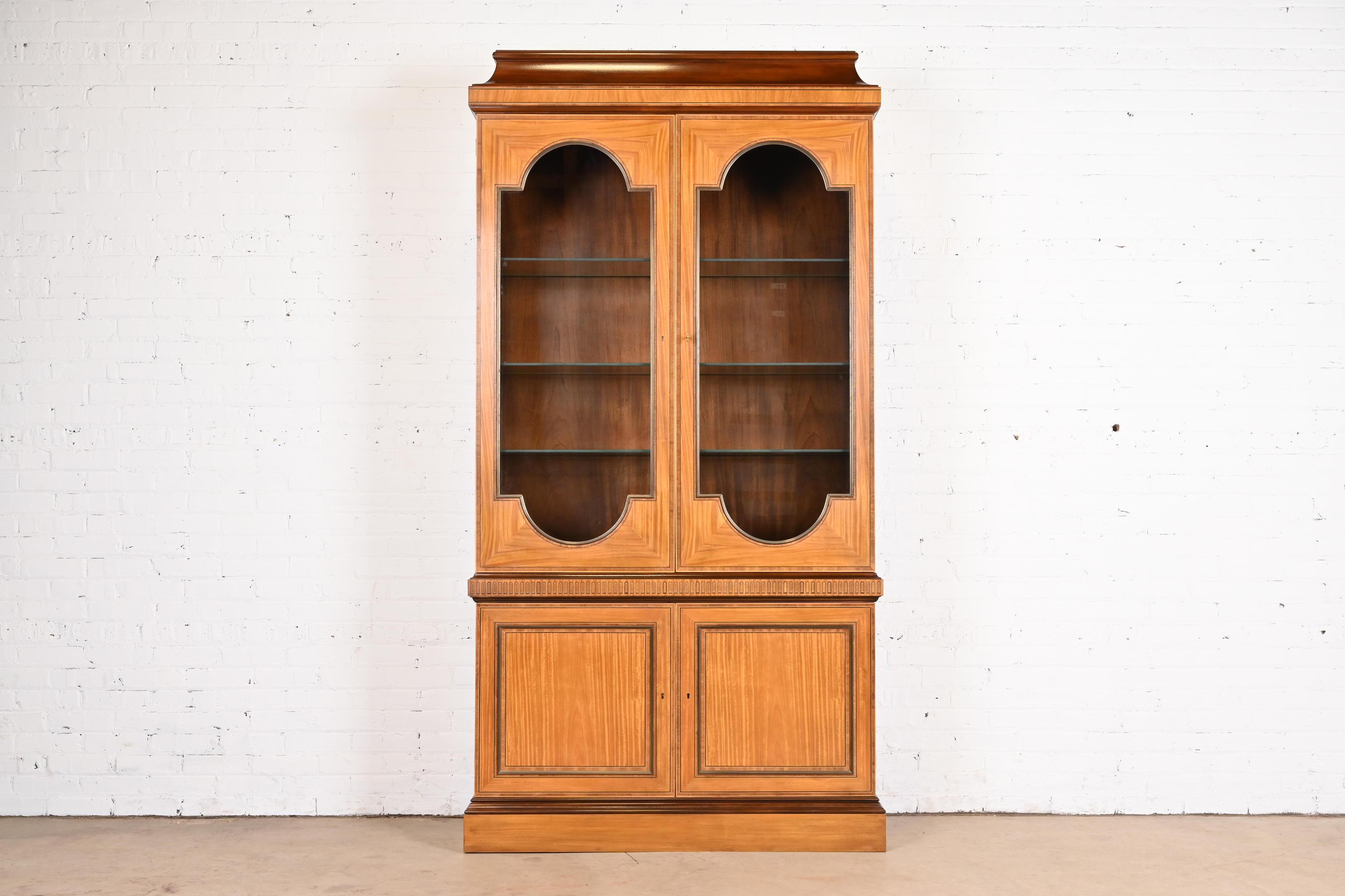 A gorgeous Neoclassical or Georgian style breakfront bookcase or dining cabinet

By Baker Furniture

USA, Late 20th Century

Beautiful satinwood and mahogany, with ebony inlay, and glass front doors. Cabinet locks, and key is included.

Measures: