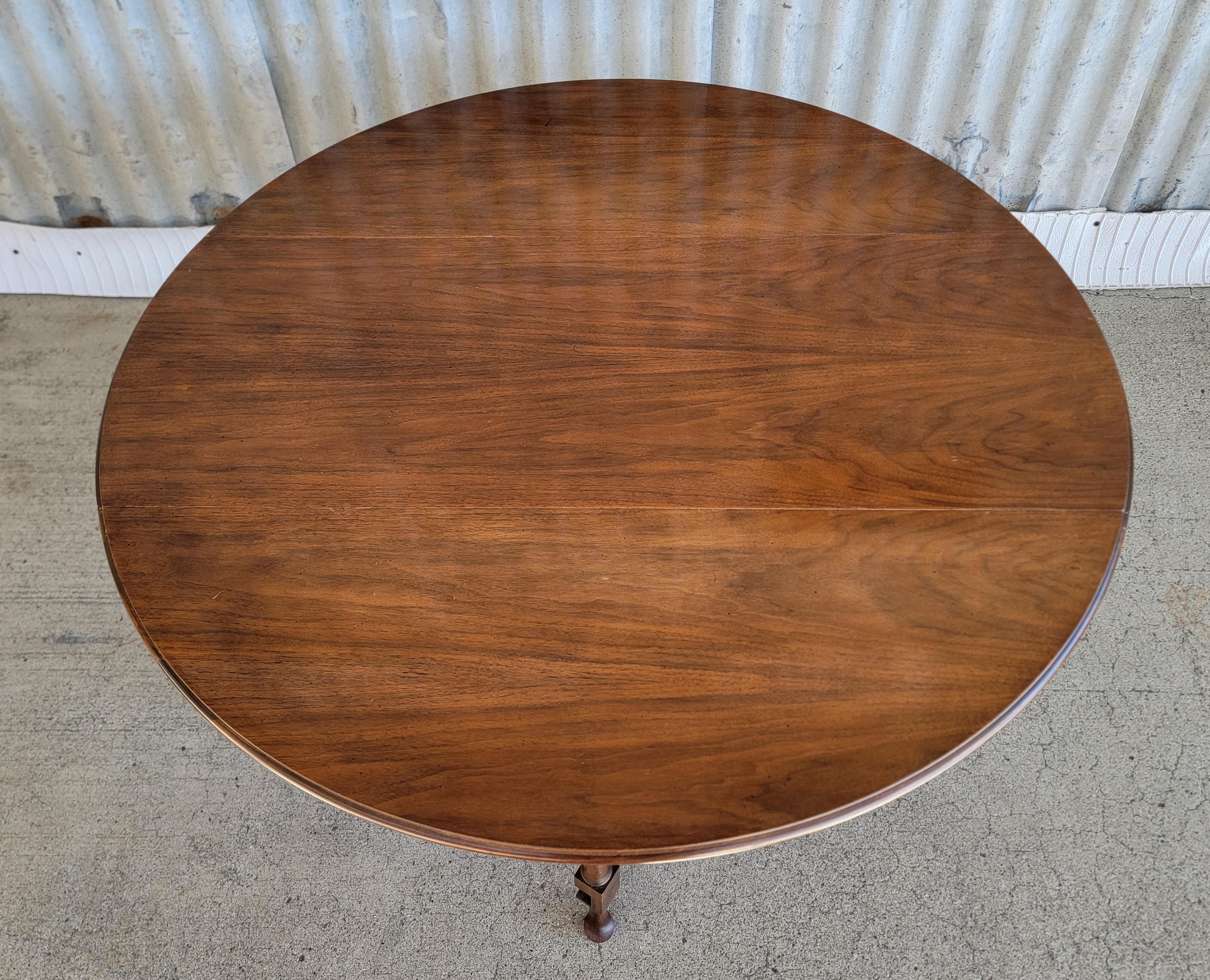 A Queen Anne style drop-leaf coffee table in walnut. Excellent original condition. Retains Baker metal label. 

Diameter 38 inches.
Height 18.5 inches.
When dropped 15.75 inches deep.