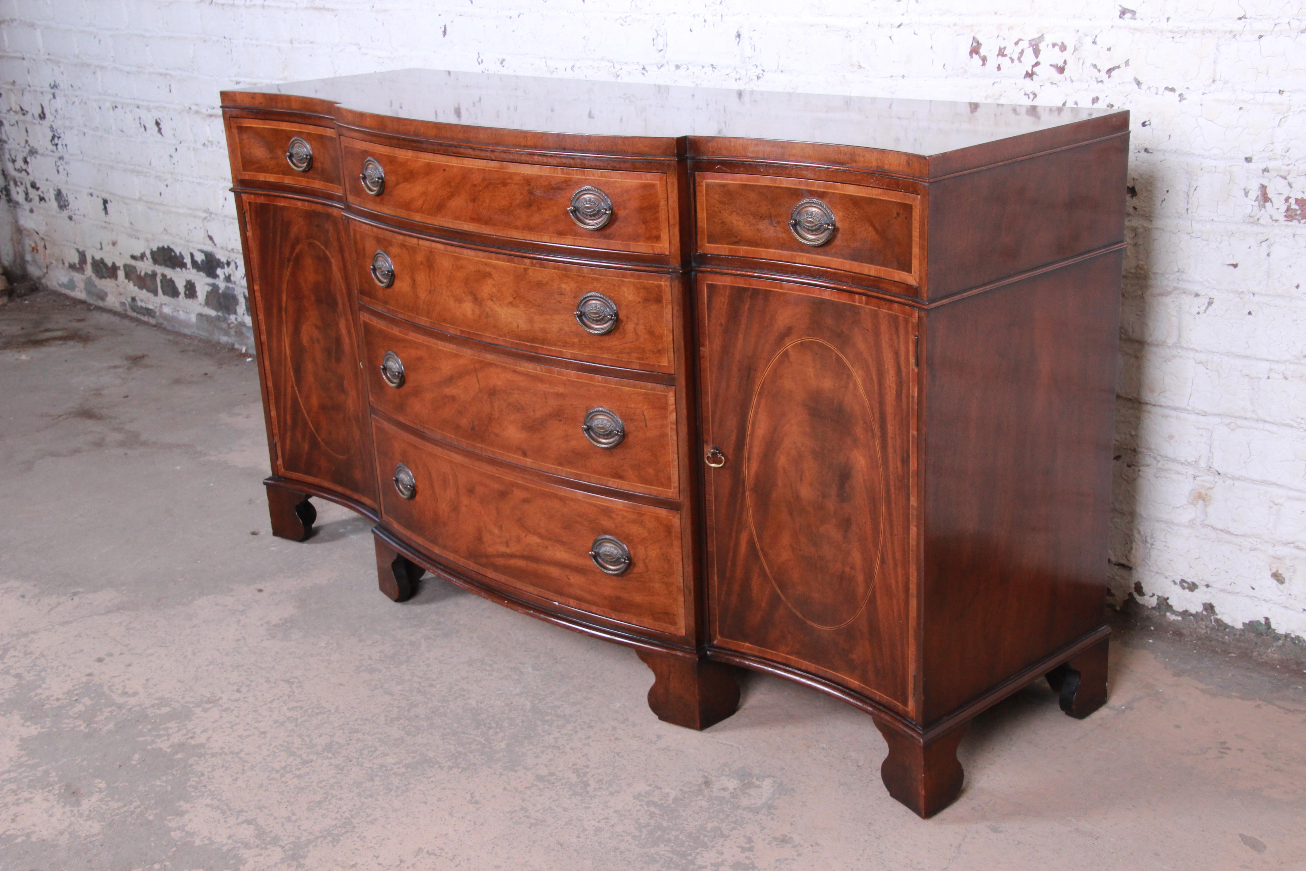 A gorgeous Regency style banded inlaid mahogany sideboard or credenza

By Baker Furniture

USA, circa 1940s

Bookmatched flame mahogany and original brass hardware

Measures: 64