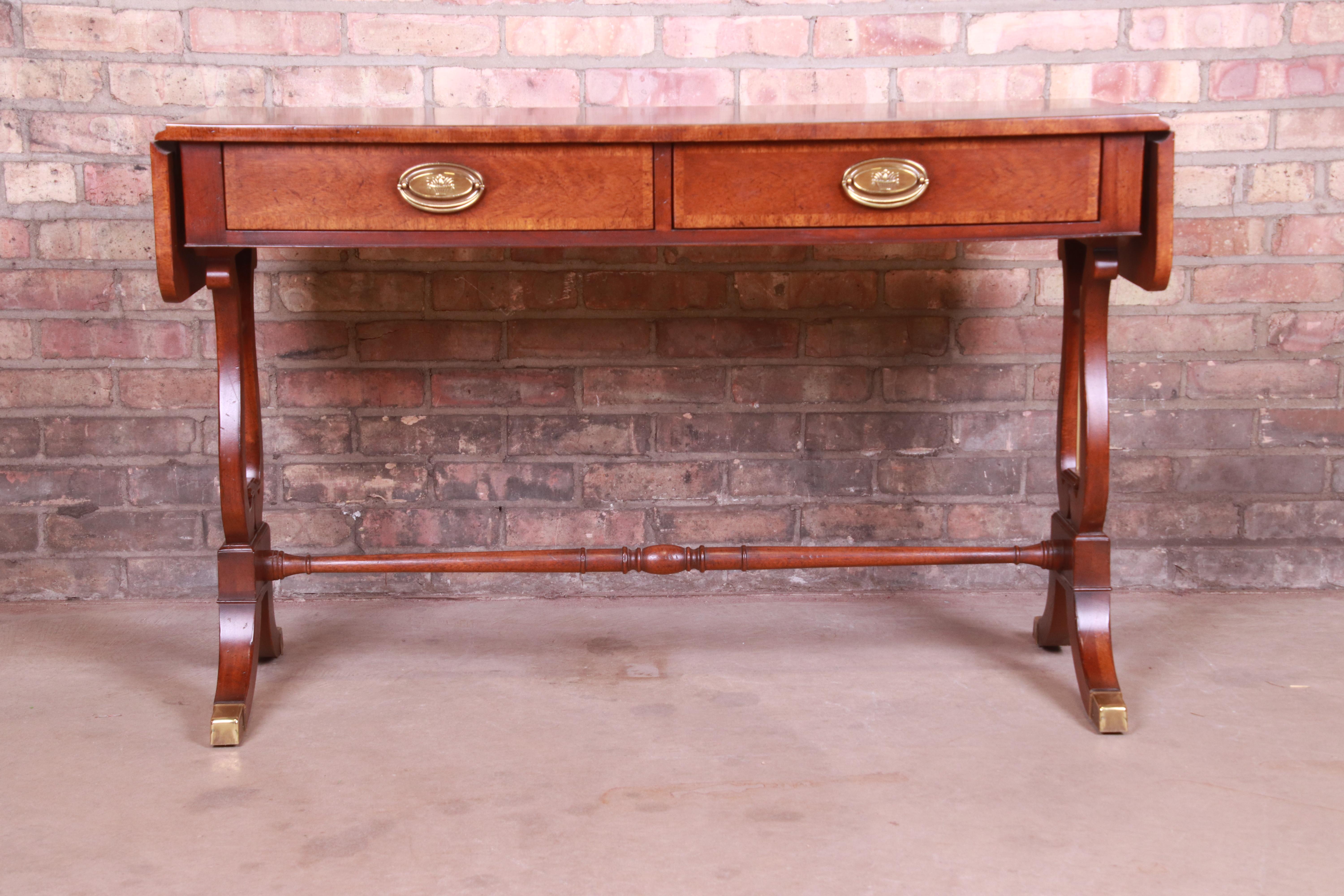 An exceptional Regency style drop leaf console or sofa table

By Baker Furniture

USA, late 20th century

Banded mahogany, with solid mahogany lyre-shaped legs and original brass hardware and accents.

Measures: 44.75