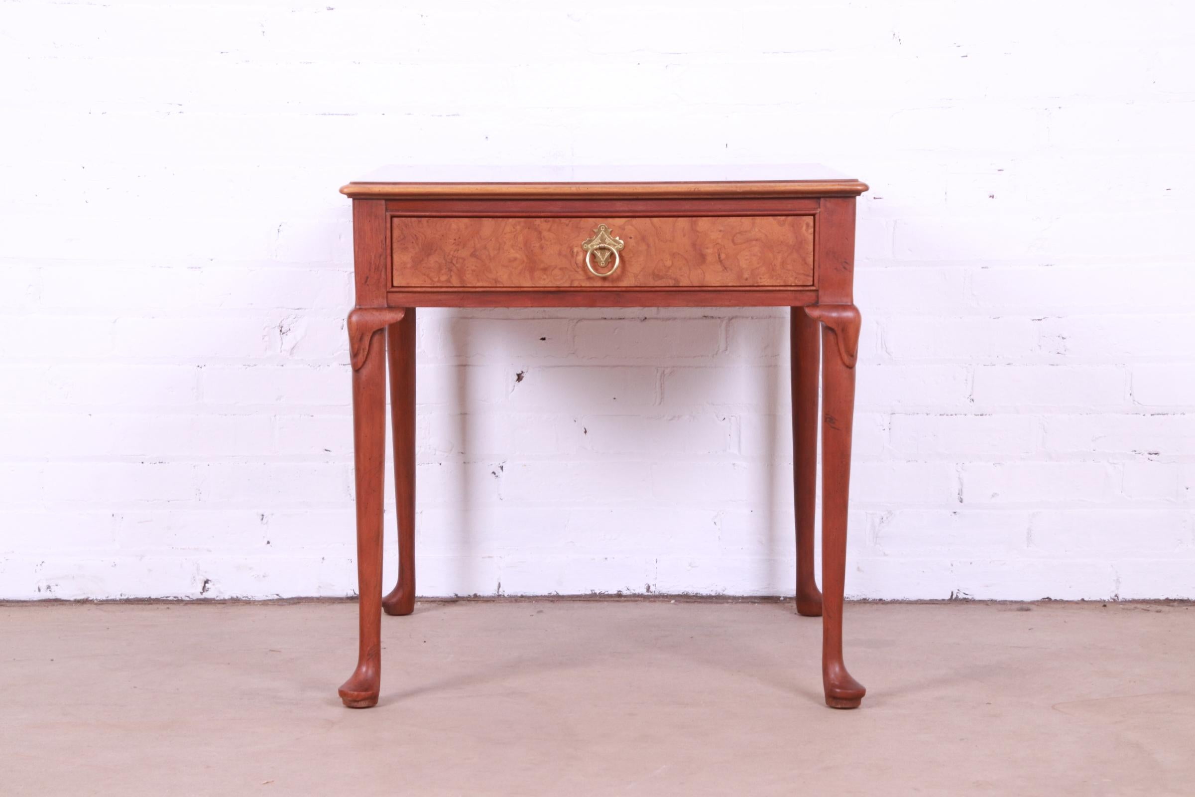 A gorgeous Regency or Queen Anne style single drawer nightstand, tea table, or occasional side table

By Baker Furniture

USA, Circa 1980s

Book-matched walnut top, carved solid walnut legs, burl wood drawer front, and original brass