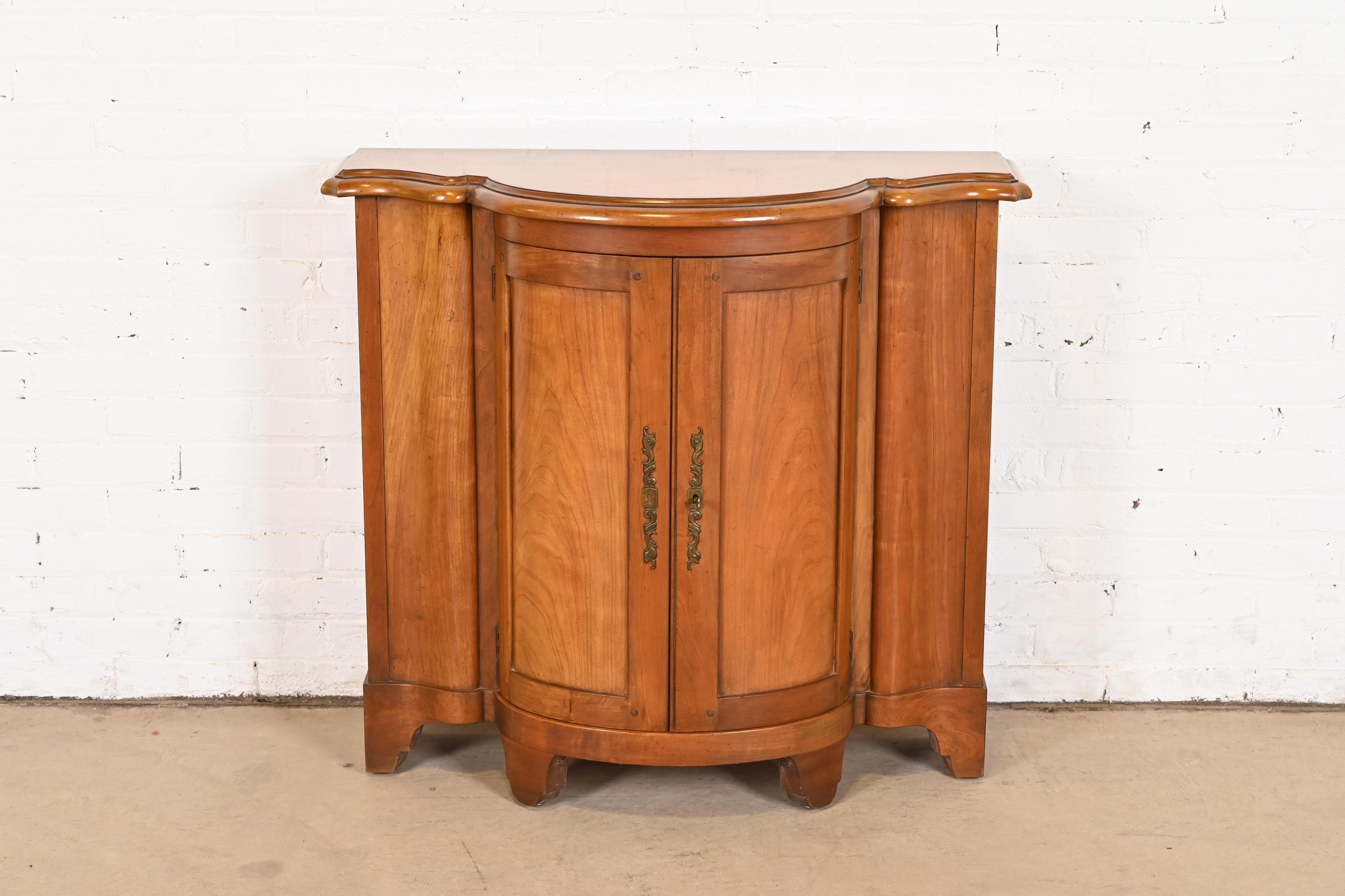 A gorgeous Regency or Georgian style demilune console or bar cabinet

By Baker Furniture

USA, Circa 1980s

Carved cherry wood, with original brass hardware.

Measures: 37.25