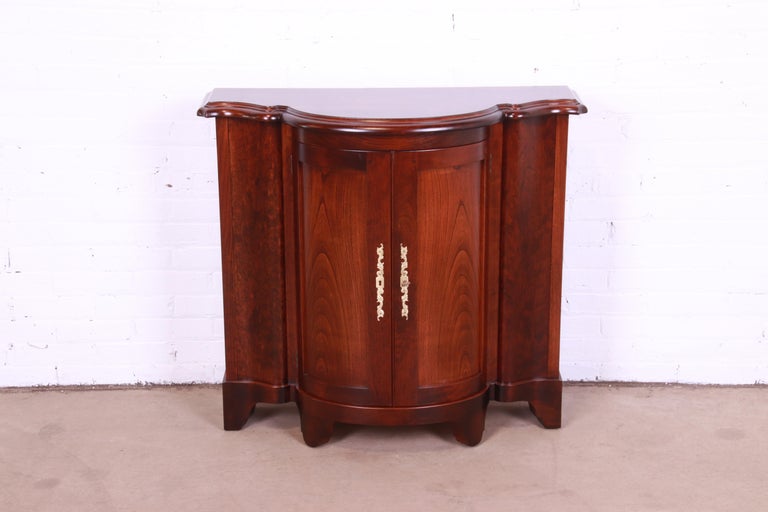 A gorgeous Regency or Georgian style demilune console or bar cabinet

By Baker Furniture

USA, Circa 1980s

Carved cherry wood, with original brass hardware.

Measures: 37