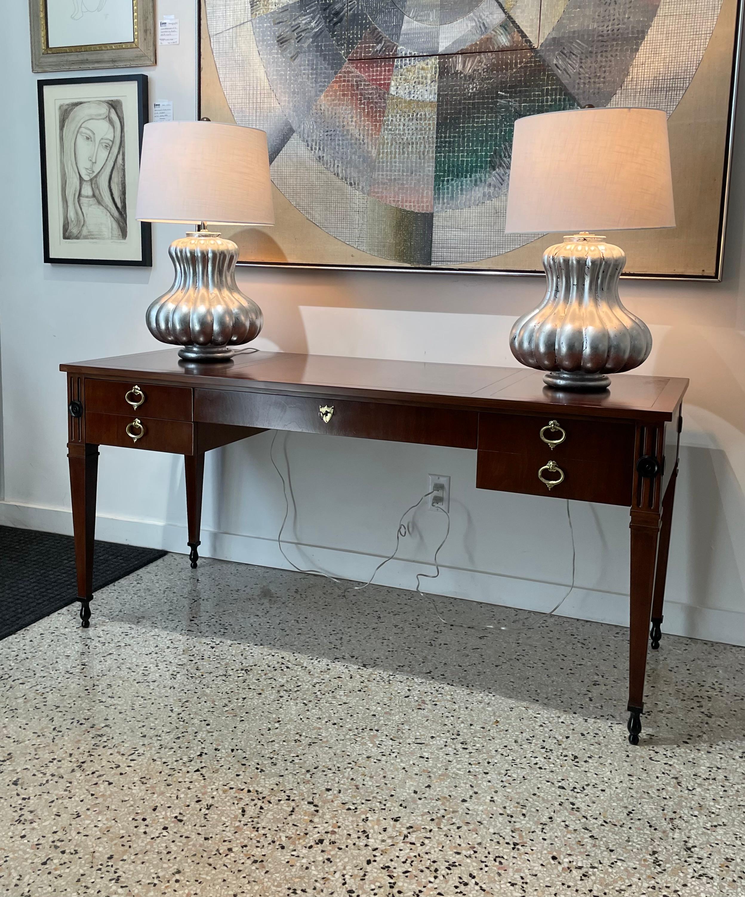 This stylish and chic Baker Furniture desk is in the Regence style with its simple form, stylized Louis XVI legs, flutes and medalions.  The top has a diamond pattern and the interior drawers are solid oak.  

Note: The piece has been professionally