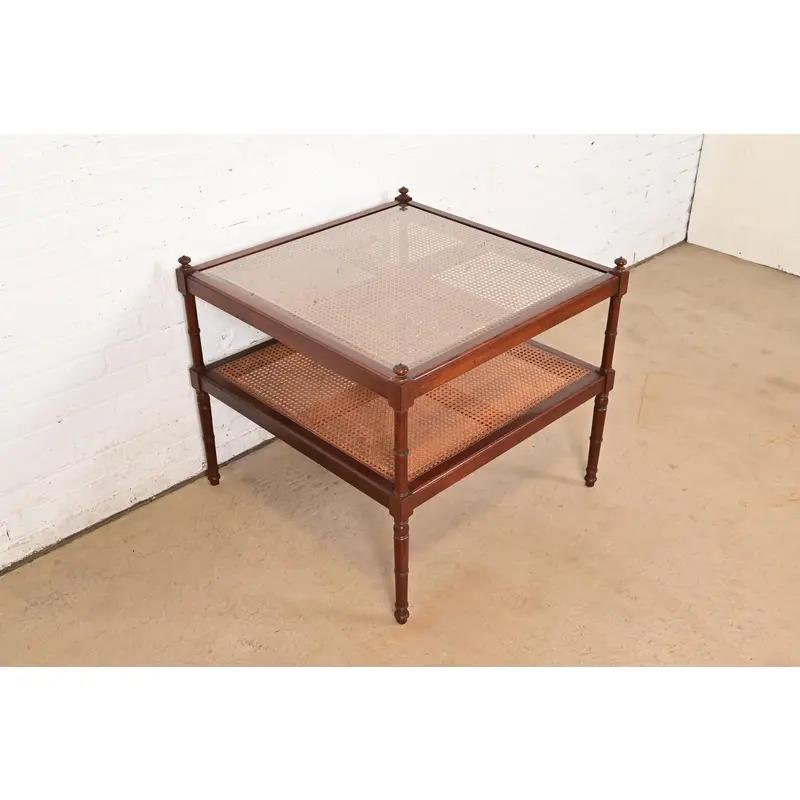 A gorgeous English Regency or British Colonial style two-tier tea table or coffee table

By Baker Furniture 

USA, Late 20th Century

Carved mahogany, with caned shelves and glass top.

Measures: 30.13