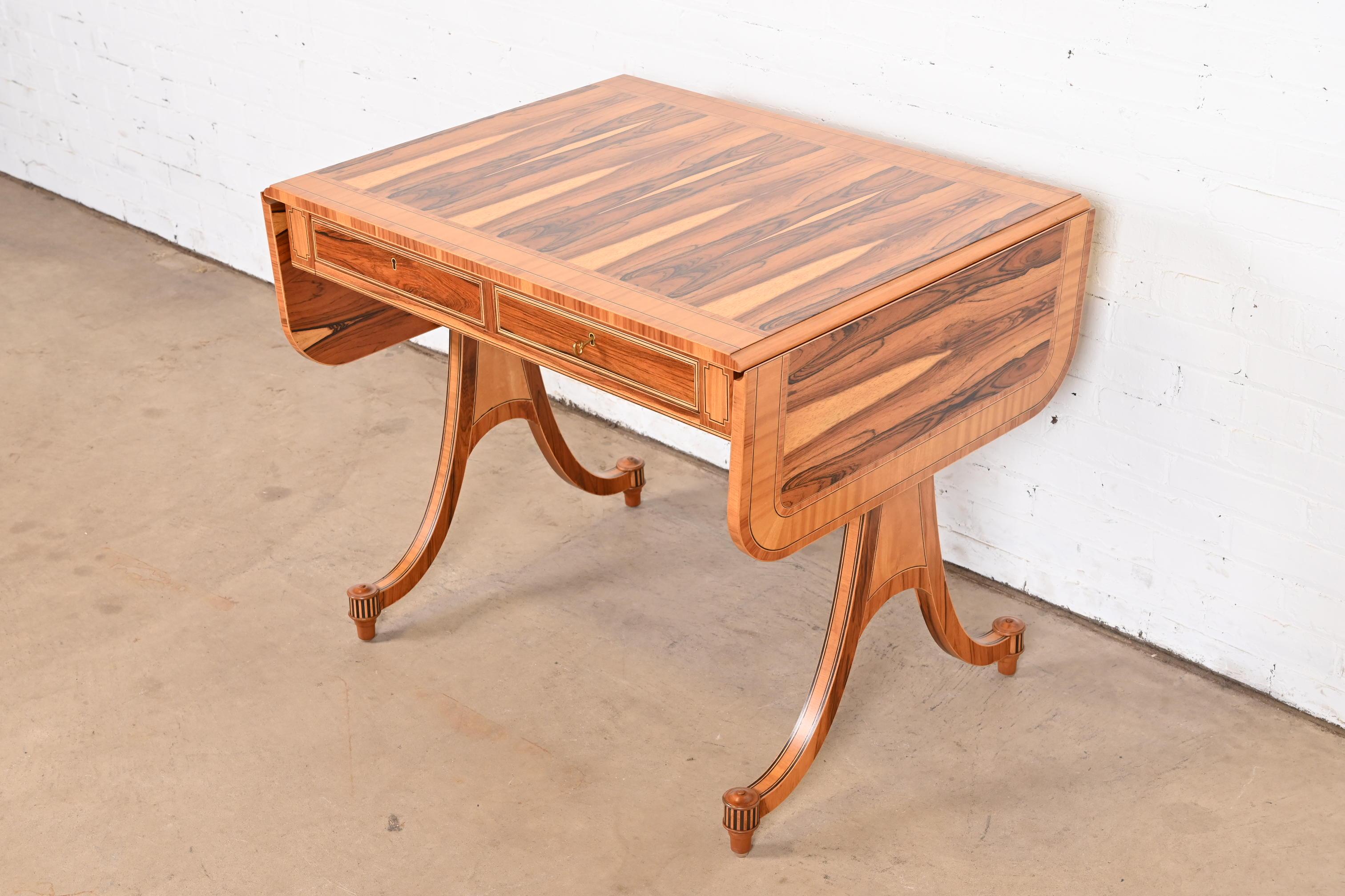 An exceptional Regency or Georgian style drop leaf writing desk, console, or sofa table

By Baker Furniture

USA, Circa 1980s

Gorgeous book-matched rosewood, with satinwood and ebony inlay.

Measures: 36