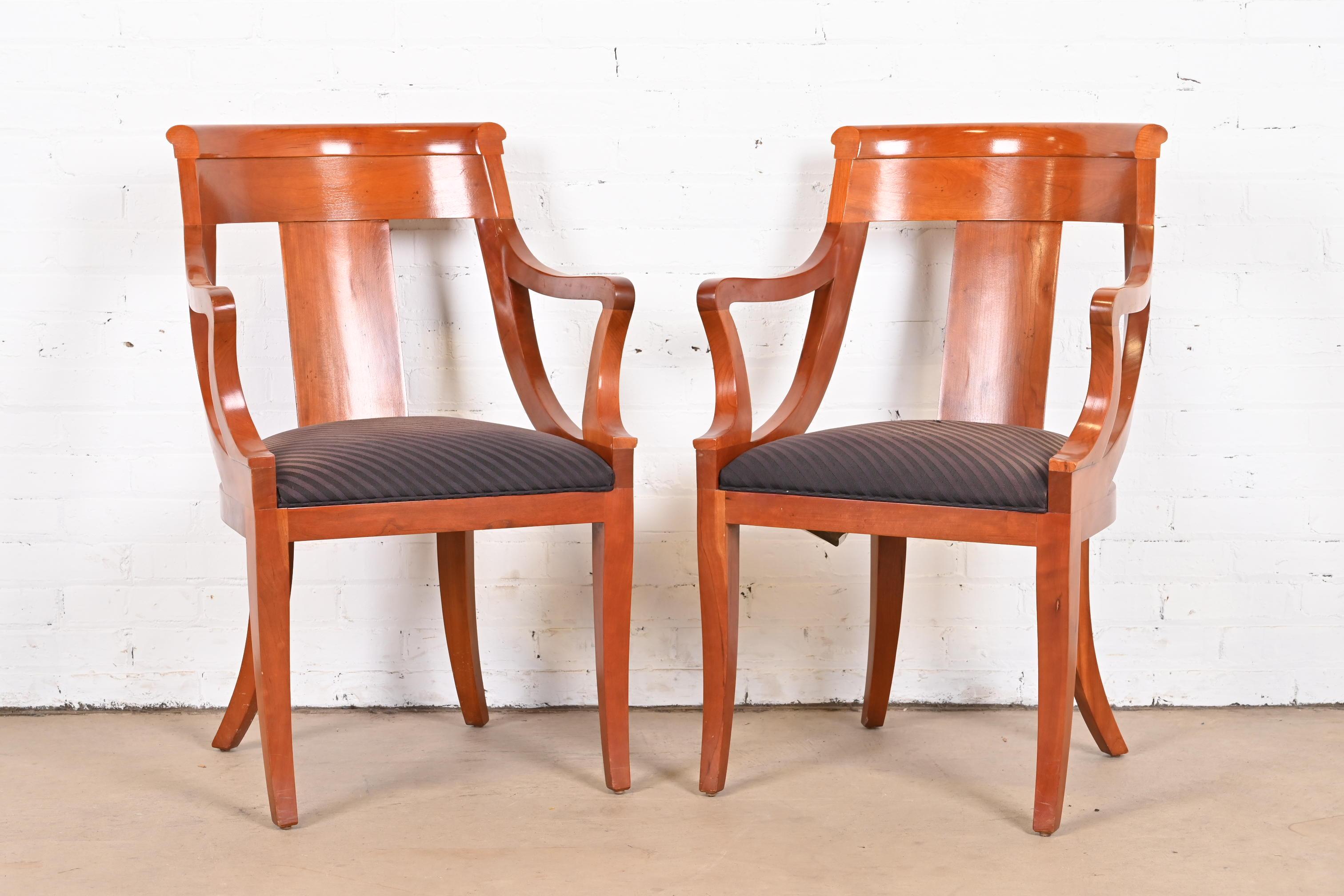 An outstanding pair of Regency or Neoclassical style dining armchairs.

By Baker Furniture.

USA, circa 1980s.

Solid cherry wood frames, with upholstered seats.

Measures: 23