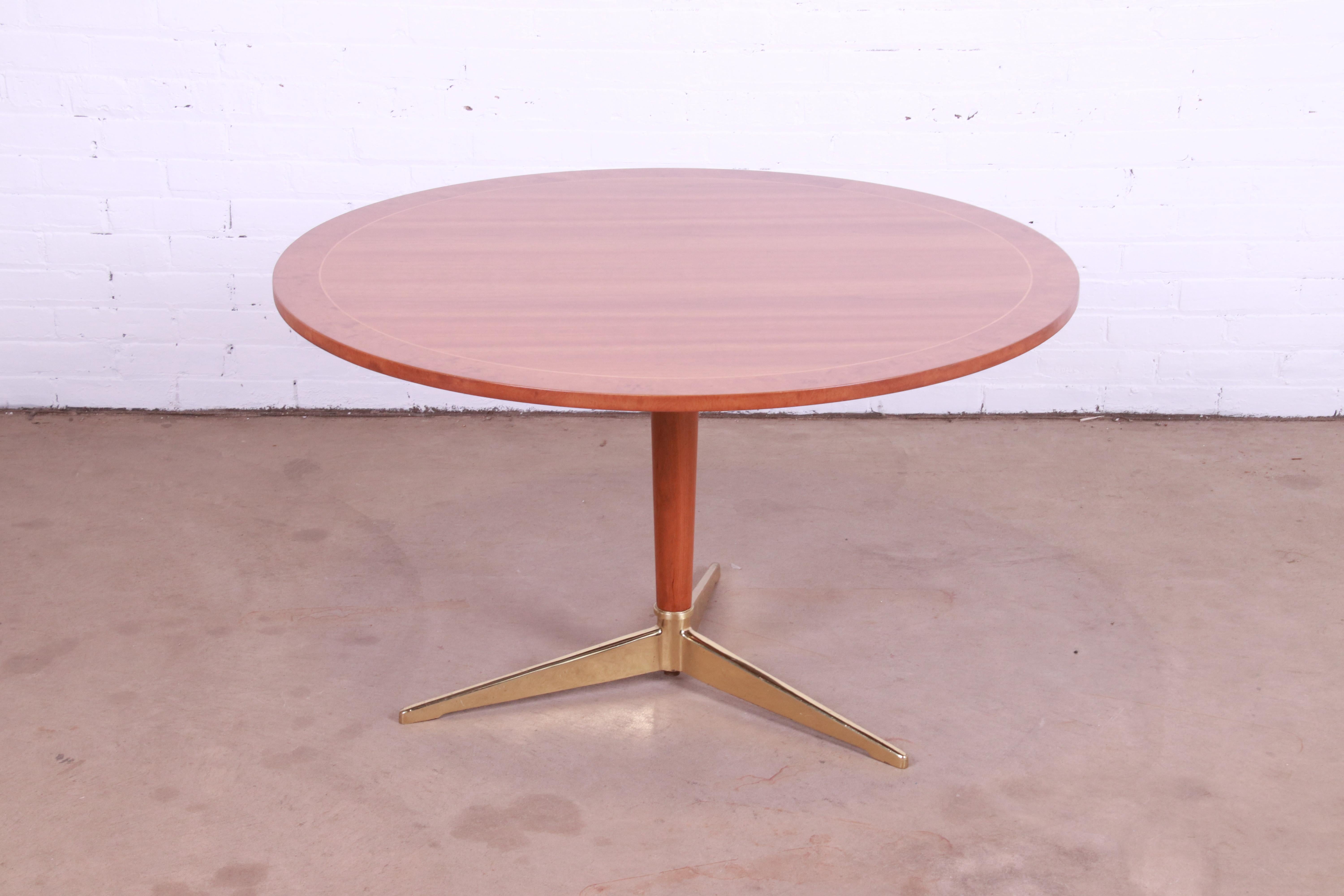 A gorgeous Mid-Century Modern pedestal game table, center table, or café table

By Baker Furniture

USA, mid-20th century

Cherry wood, with satinwood string inlay, burl wood banding, solid cherry pedestal, and brass tripod base. Featuring a