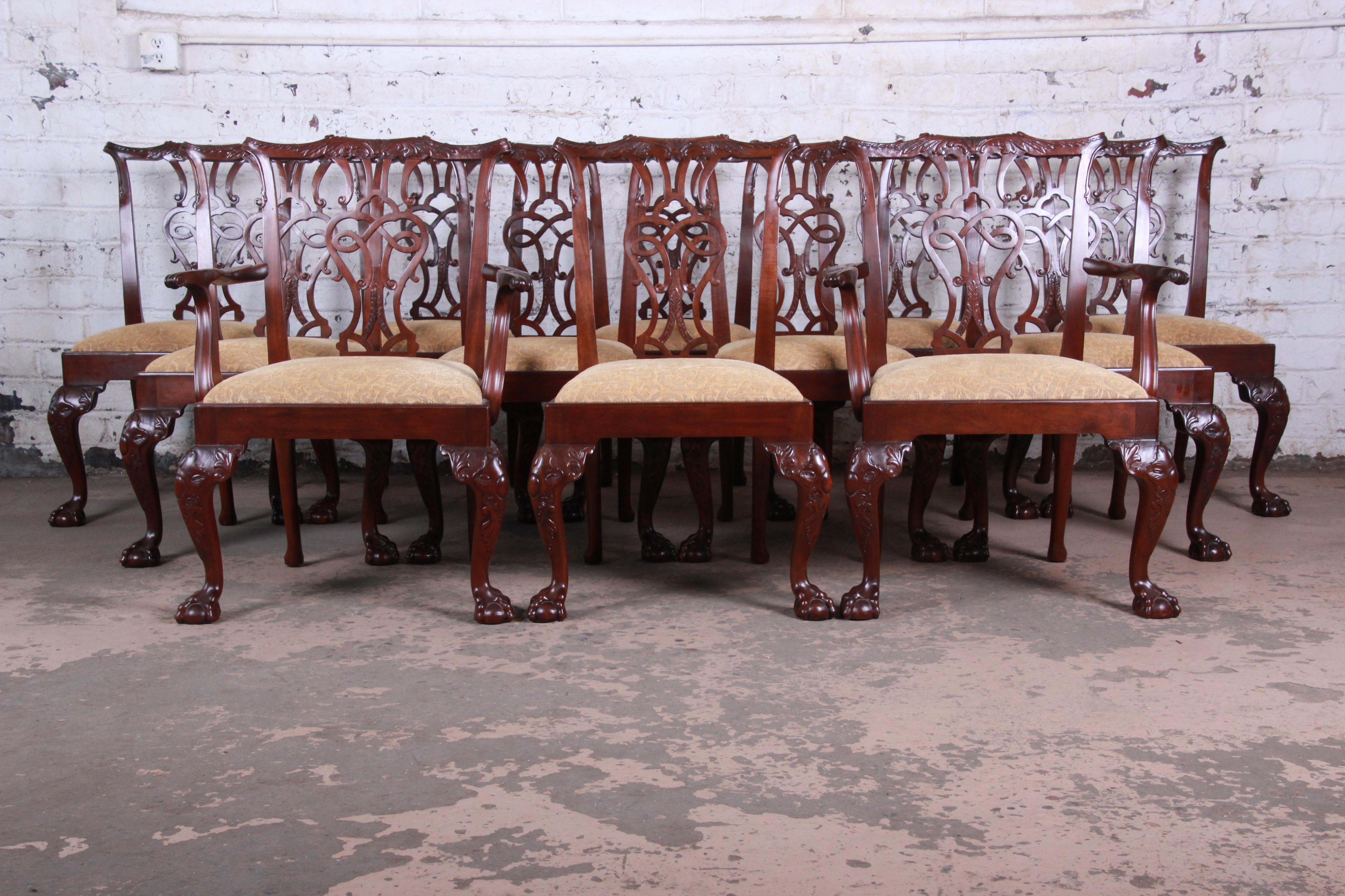 A rare and exceptional set of twelve fine Chippendale carved mahogany dining chairs from the exclusive Stately Homes collection by Baker Furniture. The set includes two open armchairs and ten side chairs. The chairs feature shaped back supports with