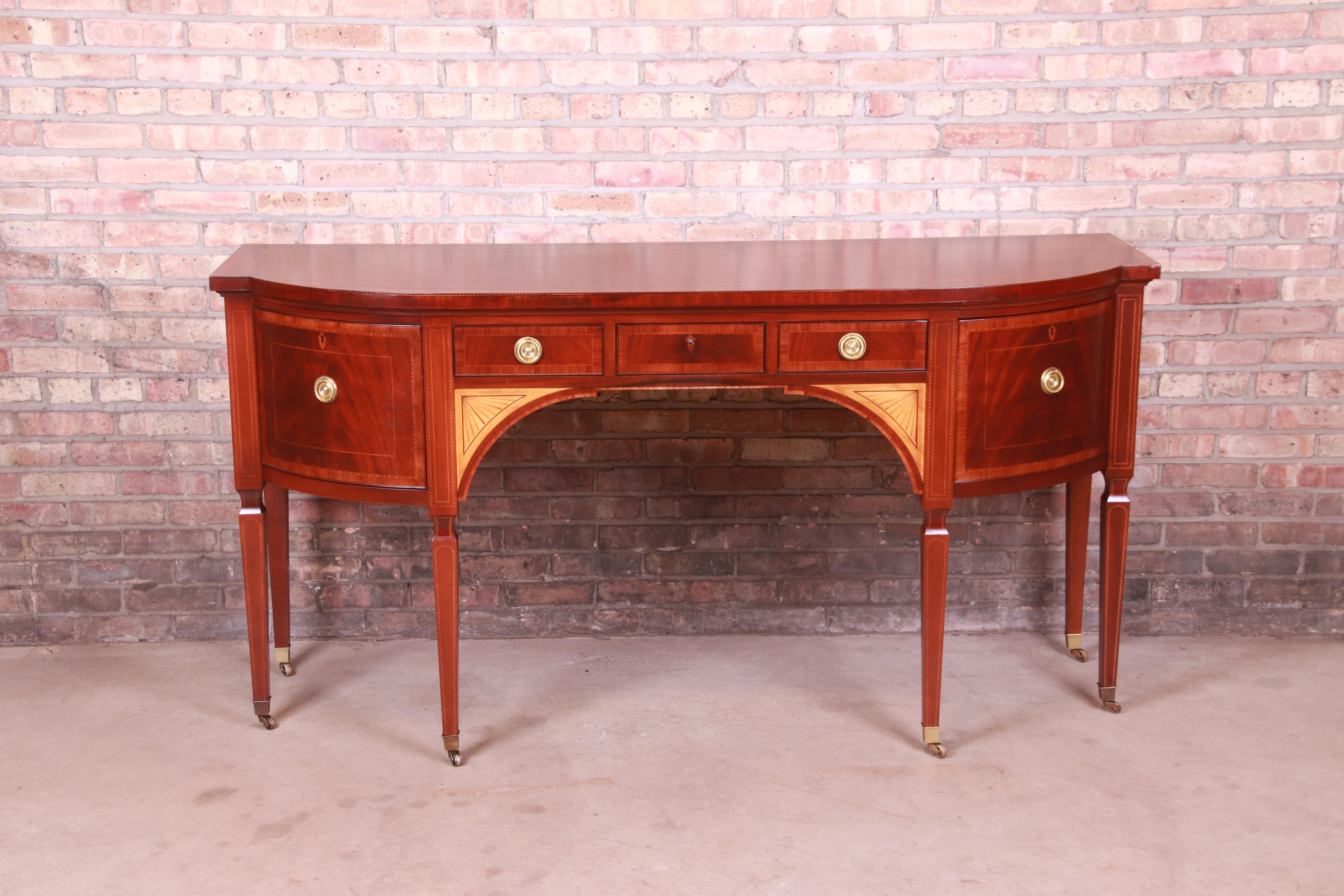 A rare and exceptional Sheraton bow-fronted mahogany sideboard from the exclusive Stately Homes Collection by Baker Furniture.

The sideboard is crossbanded with satinwood and tulipwood and inlaid with chequer pattern bands and stringing and with