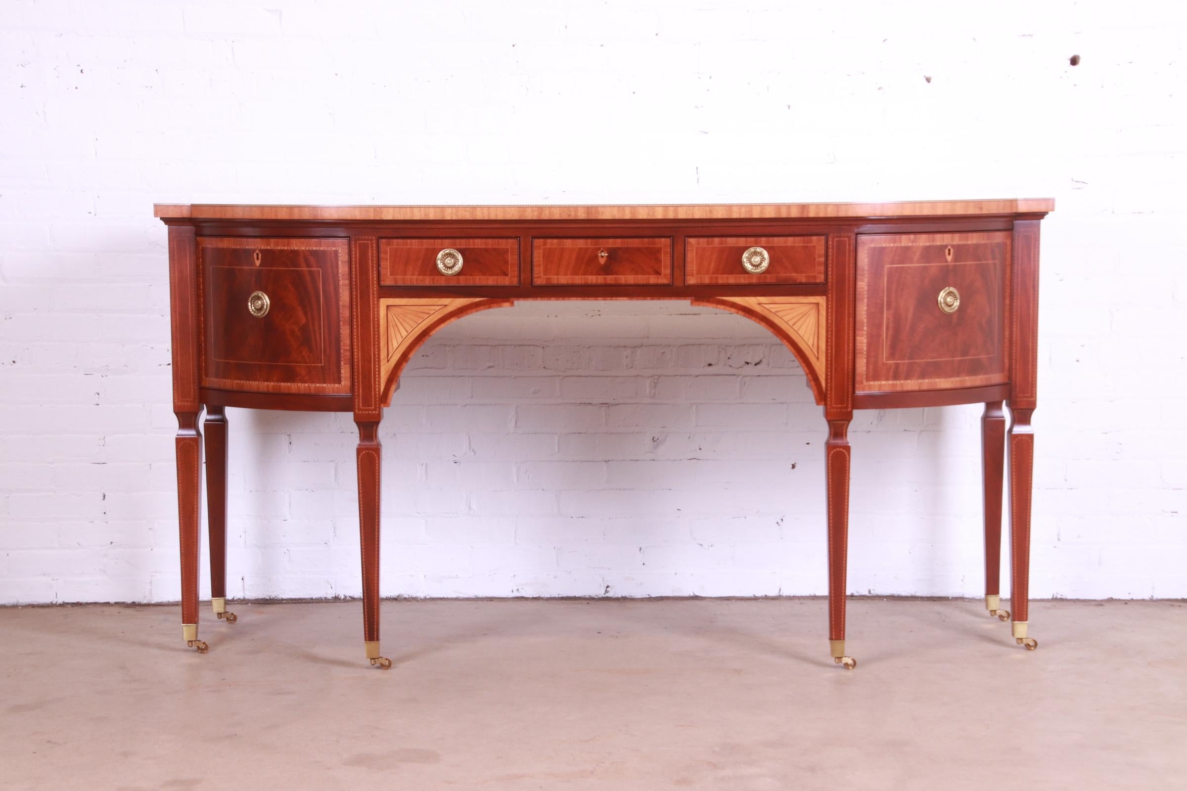 A rare and exceptional Sheraton or Hepplewhite bow-fronted mahogany sideboard from the exclusive Stately Homes Collection by Baker Furniture.

The sideboard is crossbanded with satinwood and tulipwood and inlaid with chequer pattern bands and