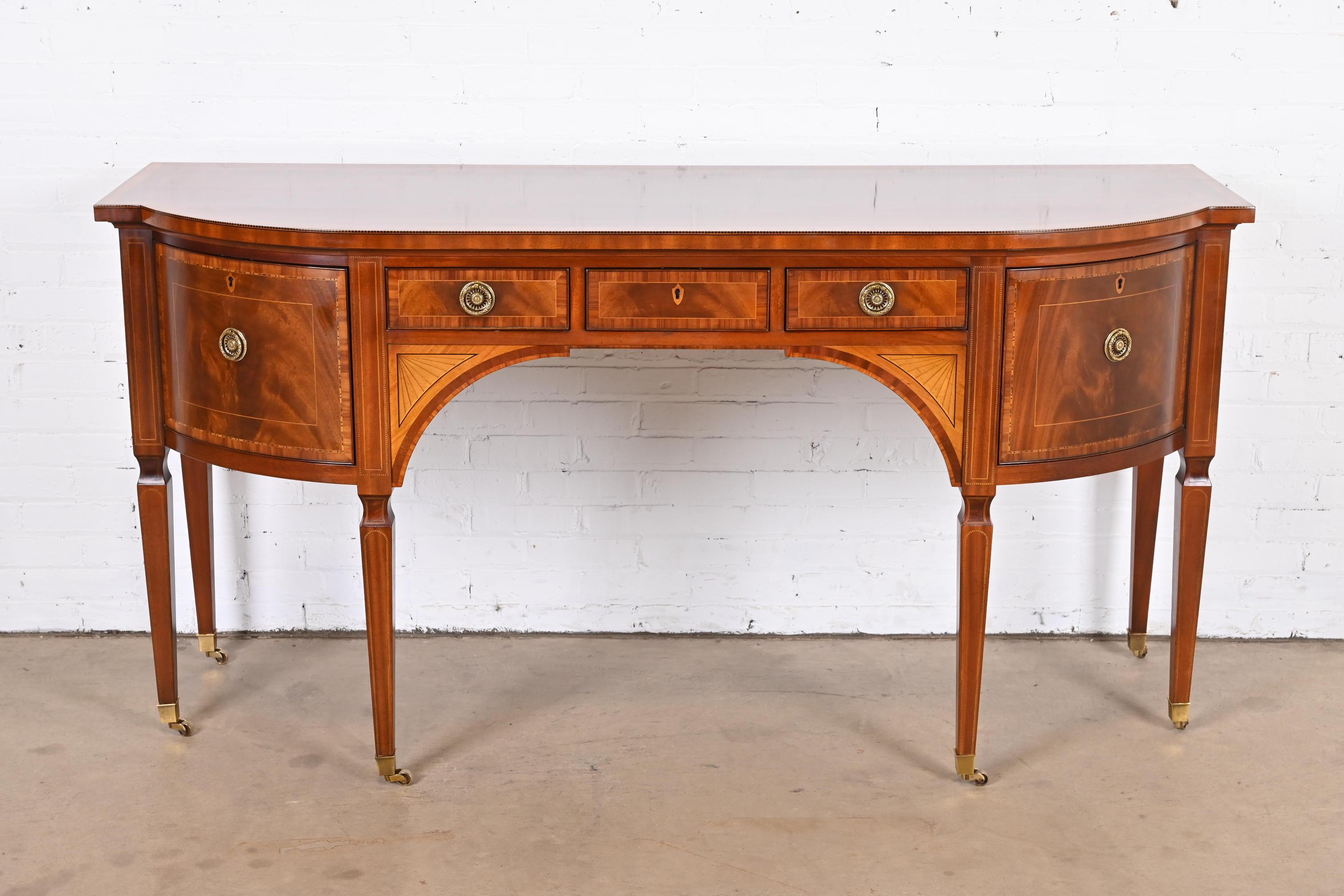 A rare and exceptional Sheraton or Hepplewhite bow-fronted mahogany sideboard from the exclusive Stately Homes Collection by Baker Furniture.

The sideboard is crossbanded with satinwood and tulipwood and inlaid with chequer pattern bands and