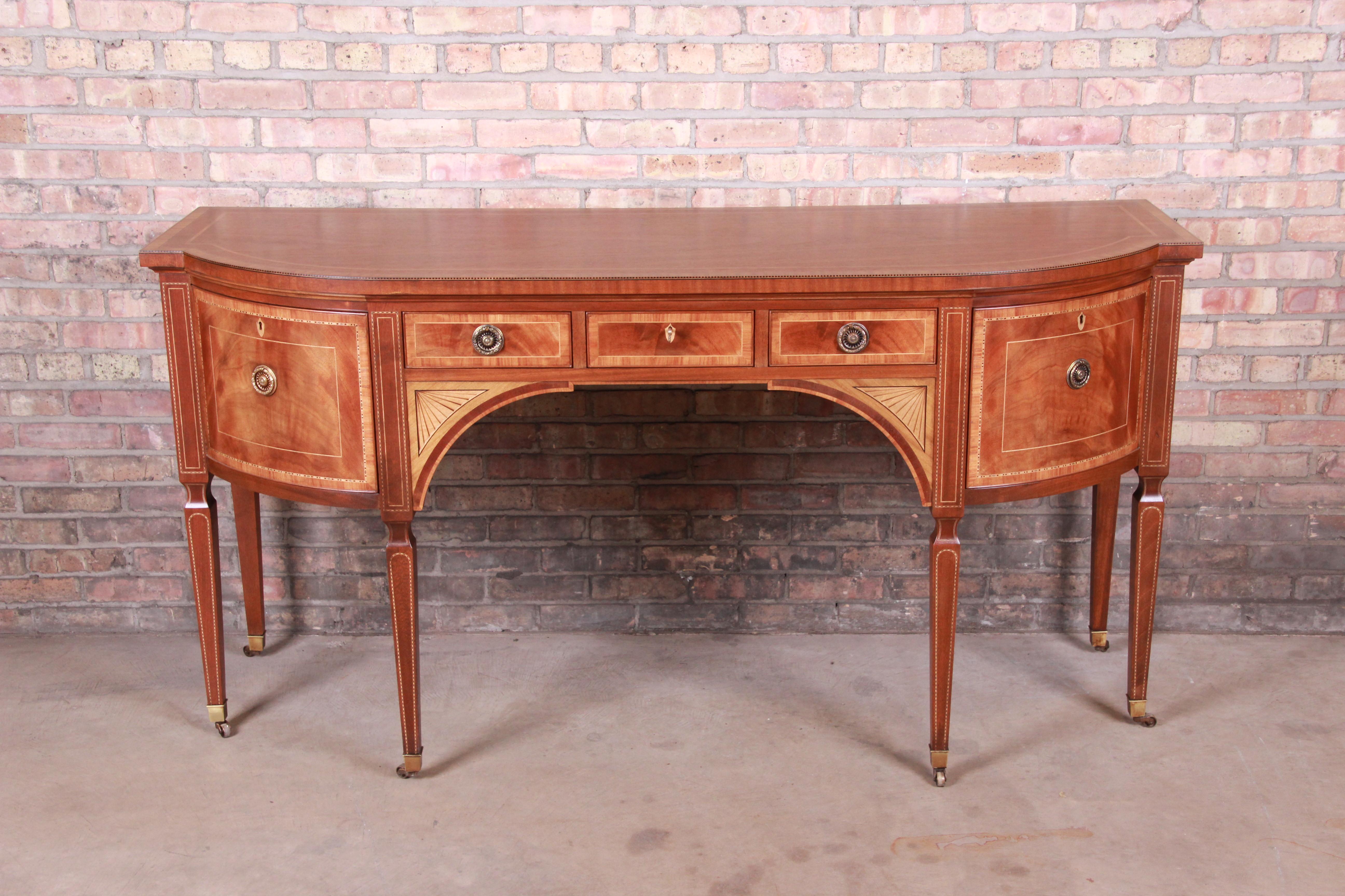 A truly rare and exceptional Sheraton bow-fronted mahogany sideboard from the exclusive Stately Homes Collection by Baker Furniture.

The sideboard is crossbanded with satinwood and tulipwood and inlaid with chequer pattern bands and stringing and