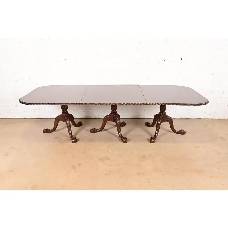 A gorgeous Chippendale or Georgian style triple pedestal extension dining table

In the manner of Baker Furniture

USA, Circa 1980s

Beautiful book-matched mahogany, with carved solid mahogany legs and ball and claw feet.

Measures: 76