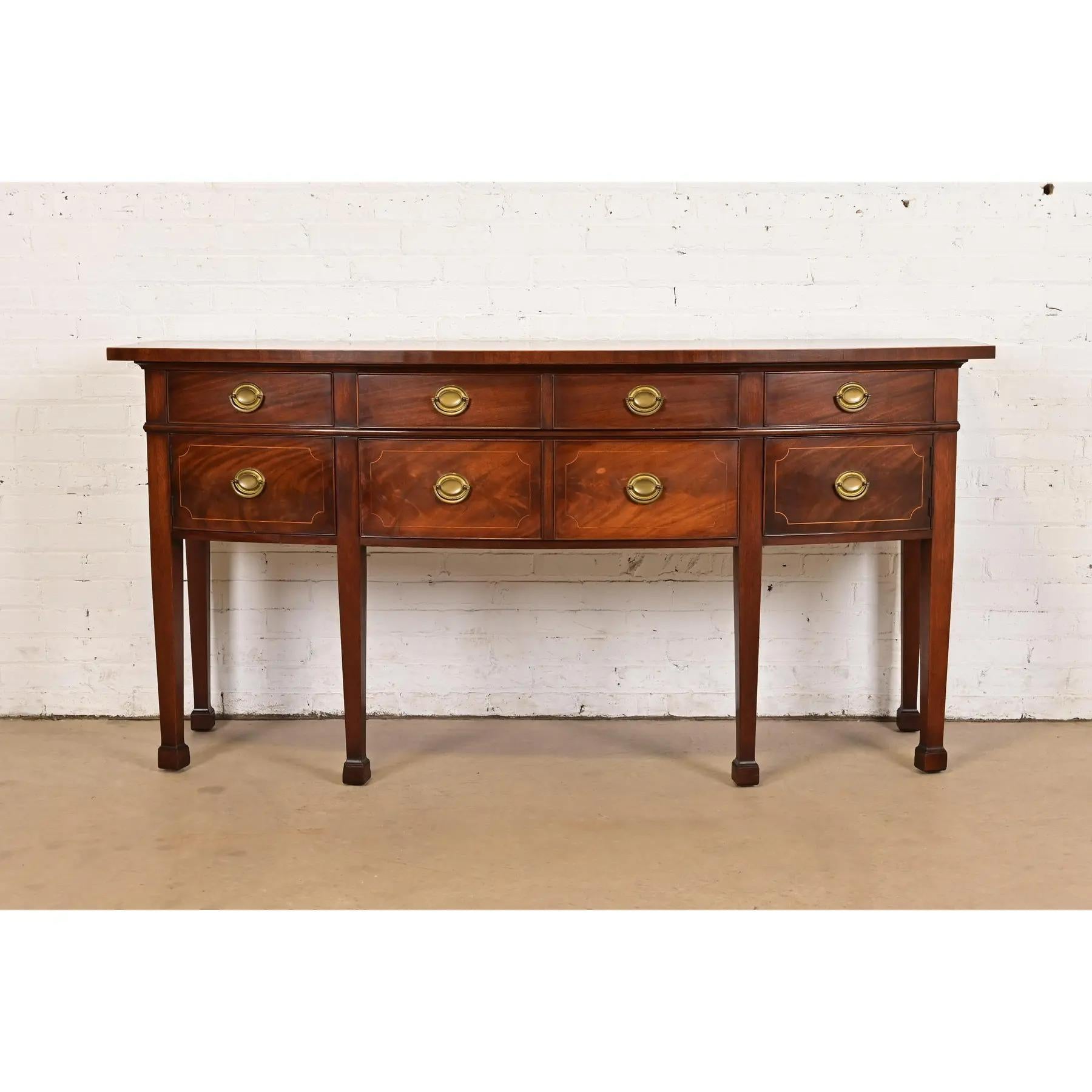 A gorgeous Hepplewhite or Federal style bow front sideboard, buffet, or credenza

In the manner of Baker Furniture

Retailed by Hathaway's of New York

USA, Circa 1920s

Beautiful flame mahogany, with satinwood string inlay, and original brass