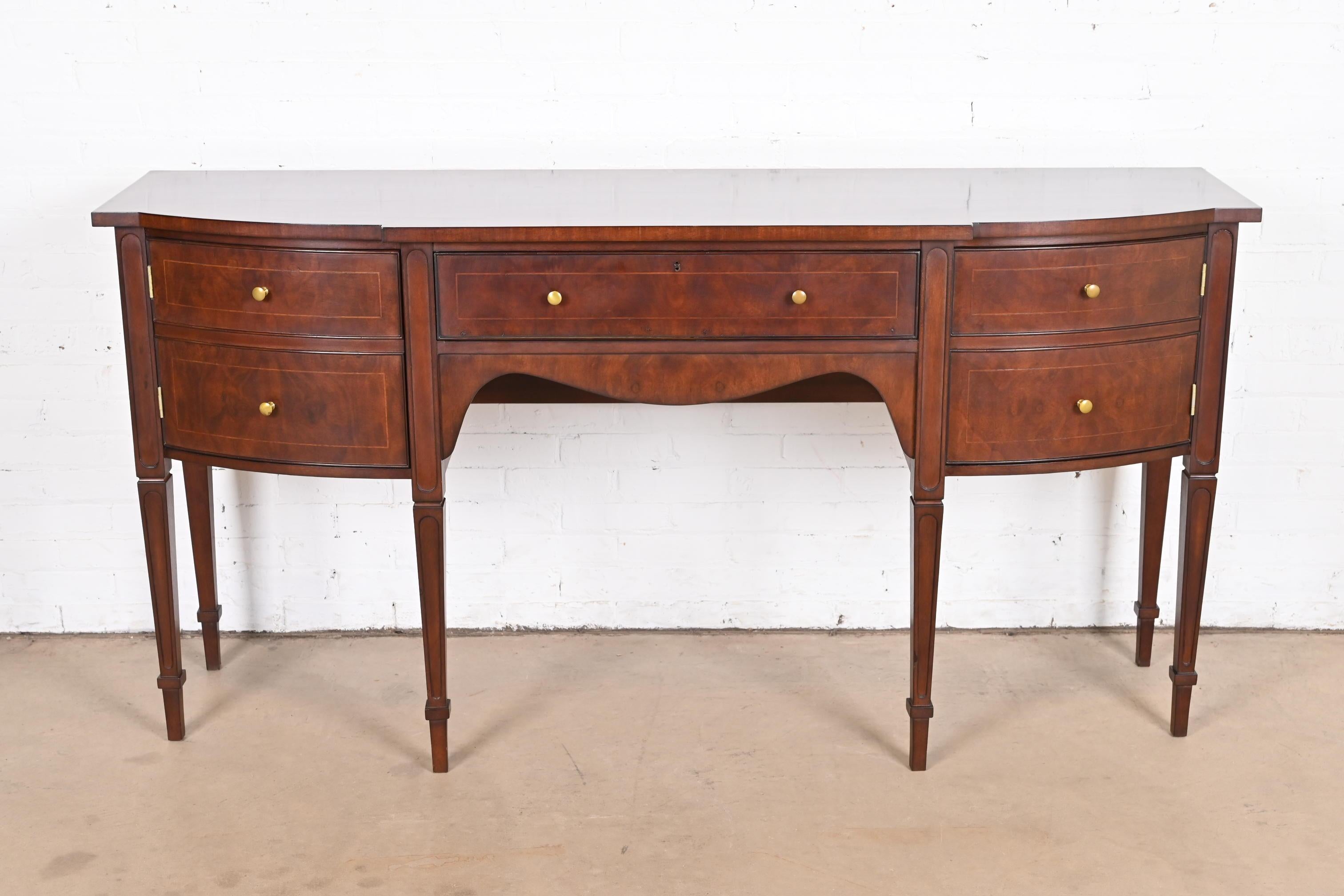 A gorgeous Hepplewhite or Federal style bow front sideboard buffet or credenza

In the manner of Baker Furniture

USA, Circa 1980s

Gorgeous burled mahogany, with satinwood string inlay, banded mahogany top, and original brass hardware.

Measures: